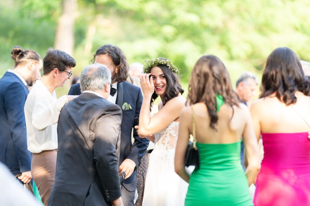Wedding guests dance and celebrate on a grassy lawn at dusk.