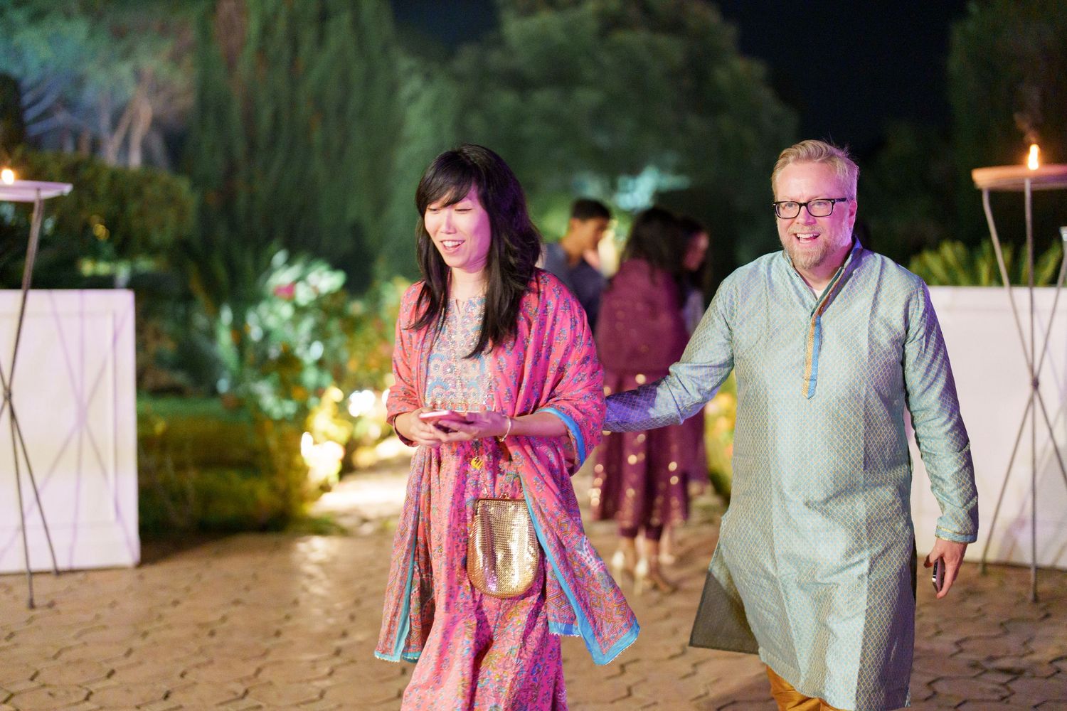Guests socializing at a nighttime outdoor celebration with ambient lighting.