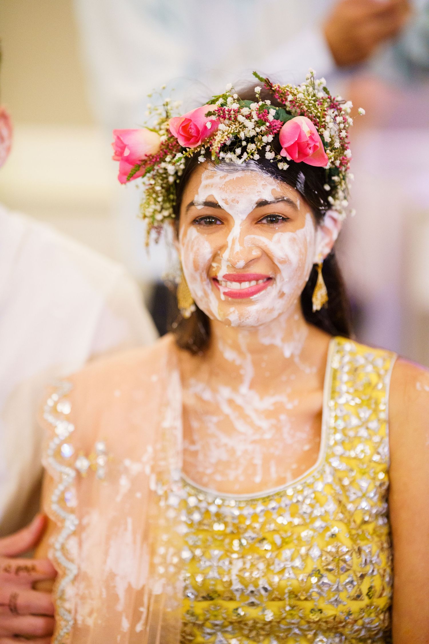 Person in a gold sequined dress wearing a floral crown with confetti on their face.