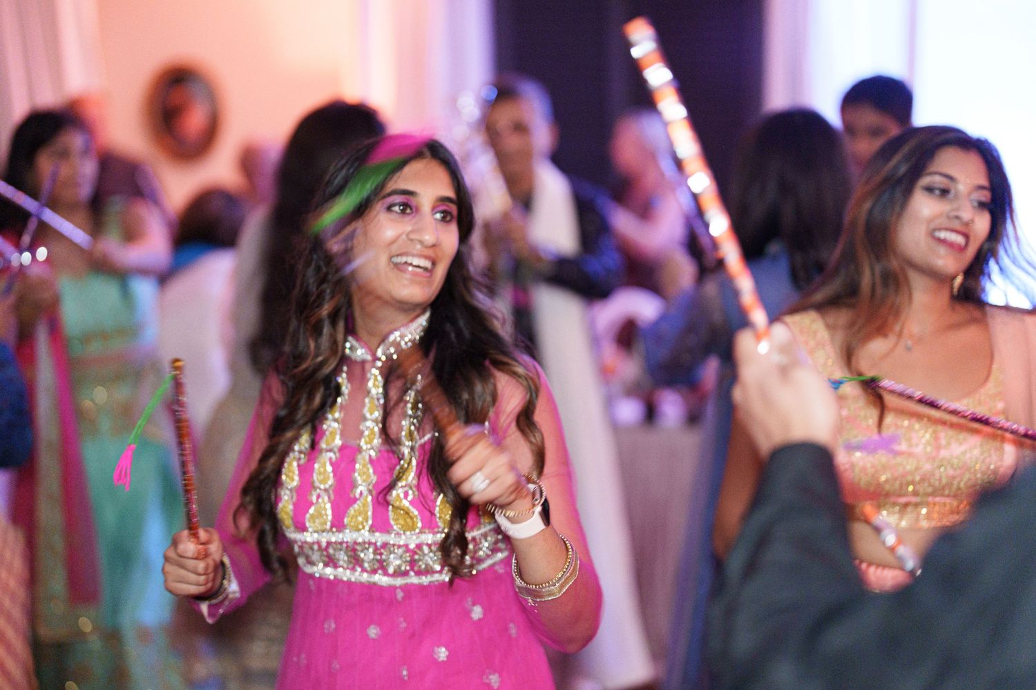 Guests in colorful traditional attire dancing with sparklers at a celebration.