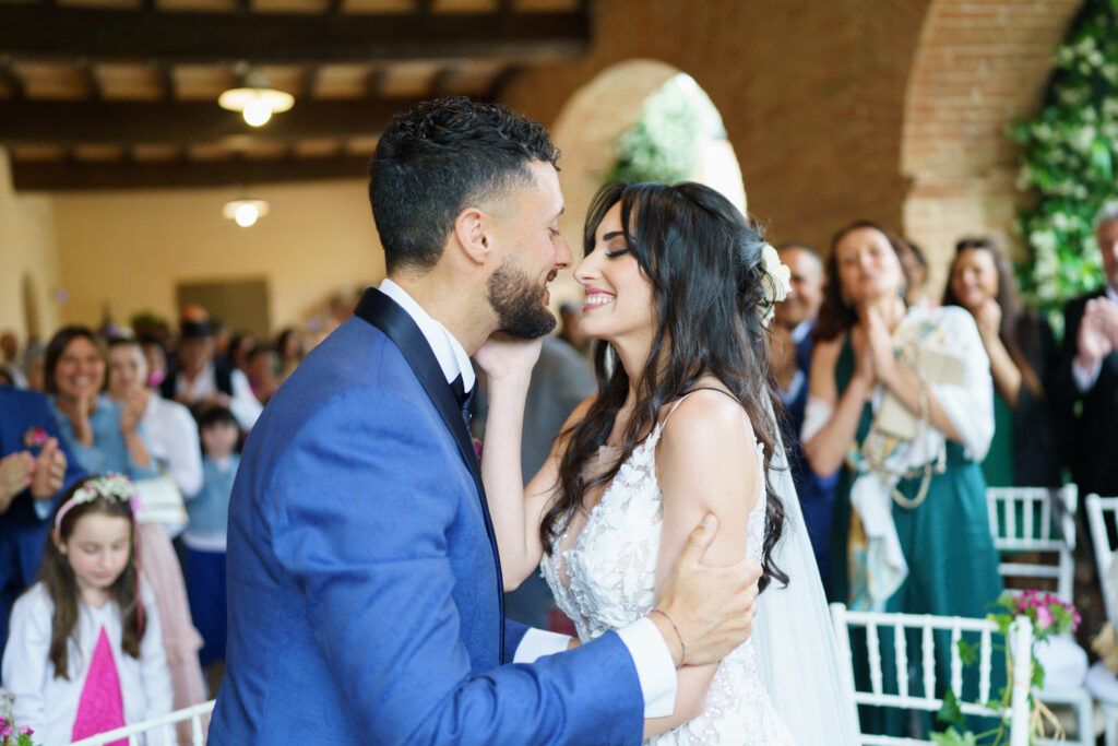 Wedding couple embraces during romantic ceremony under rustic wooden beams.