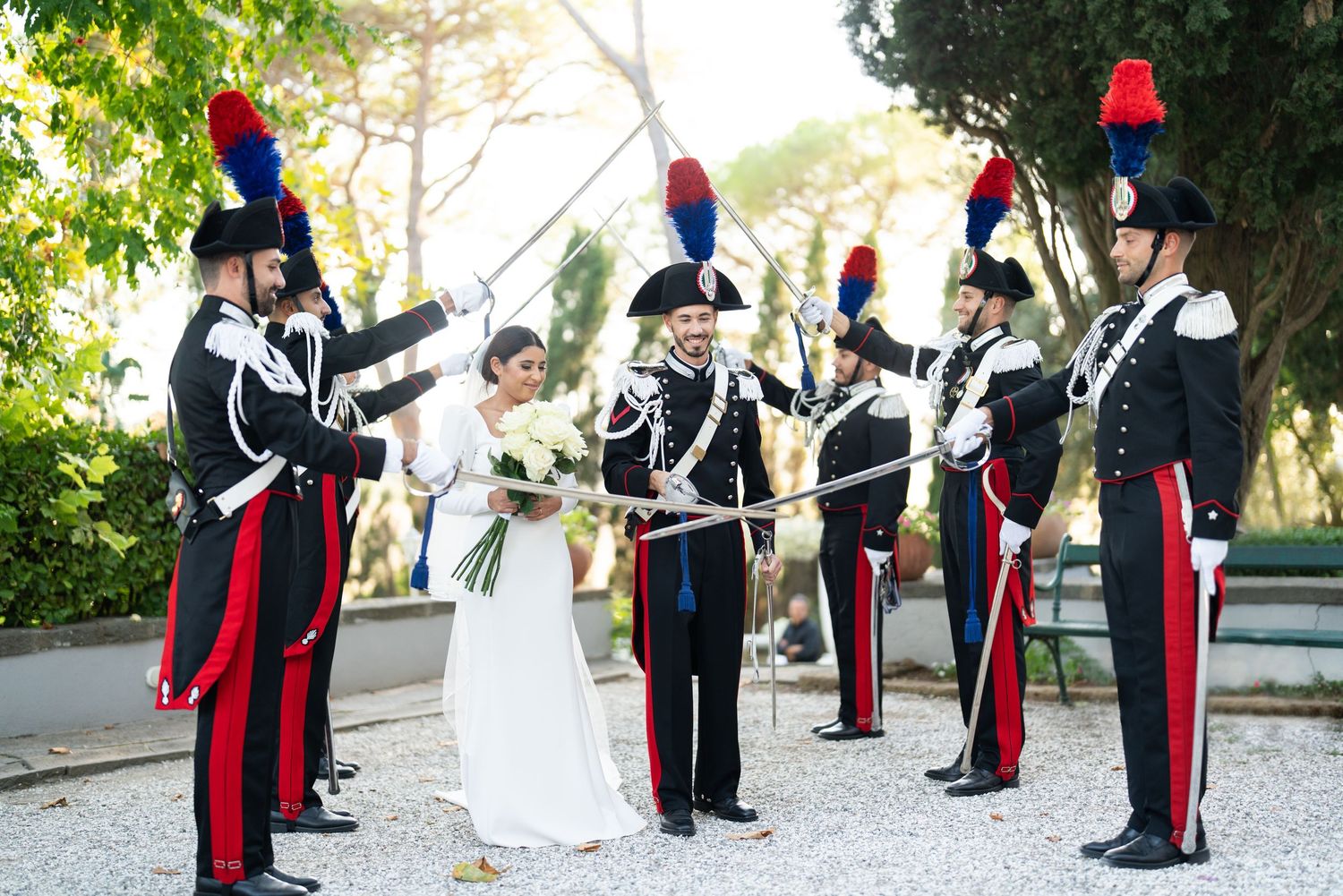 Honor guard members in formal uniforms stand at attention during outdoor wedding ceremony.