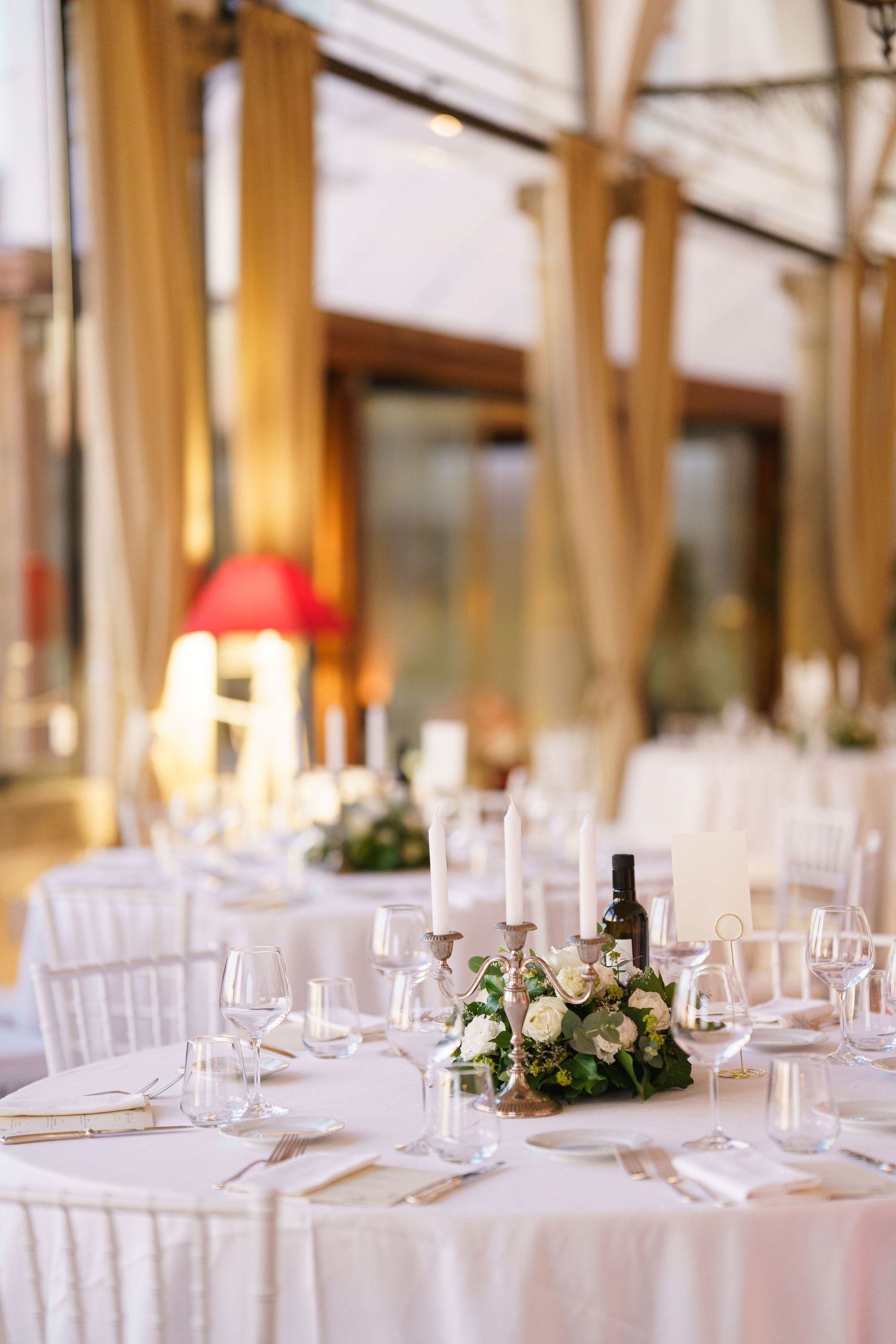Elegant white table settings with glassware and floral centerpieces at an upscale wedding reception venue.