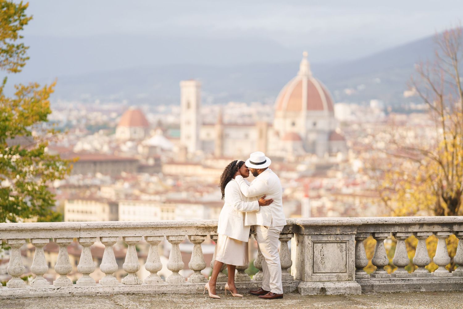 Couple kissing on a terrace in Florence, Italy, with the iconic Duomo cathedral and cityscape in the background.