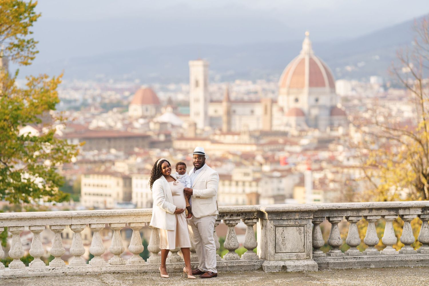 Couple in white outfits on a terrace with Florence skyline and Cathedral dome backdrop.