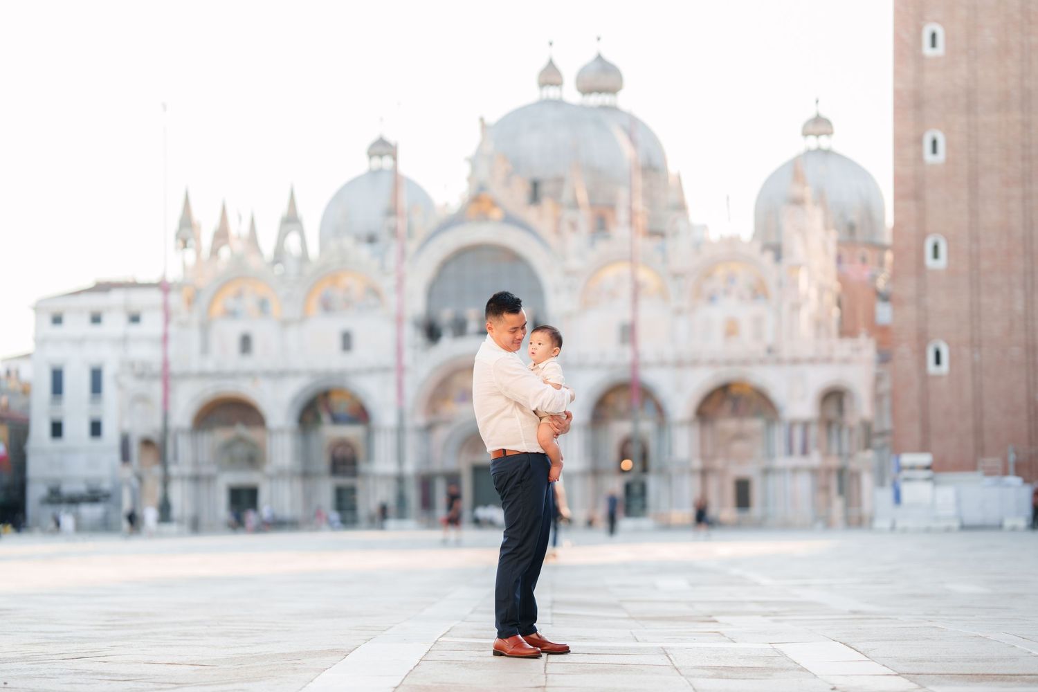 Couple sharing a tender moment in St. Mark's Square, Venice, with the iconic Basilica di San Marco in the background.