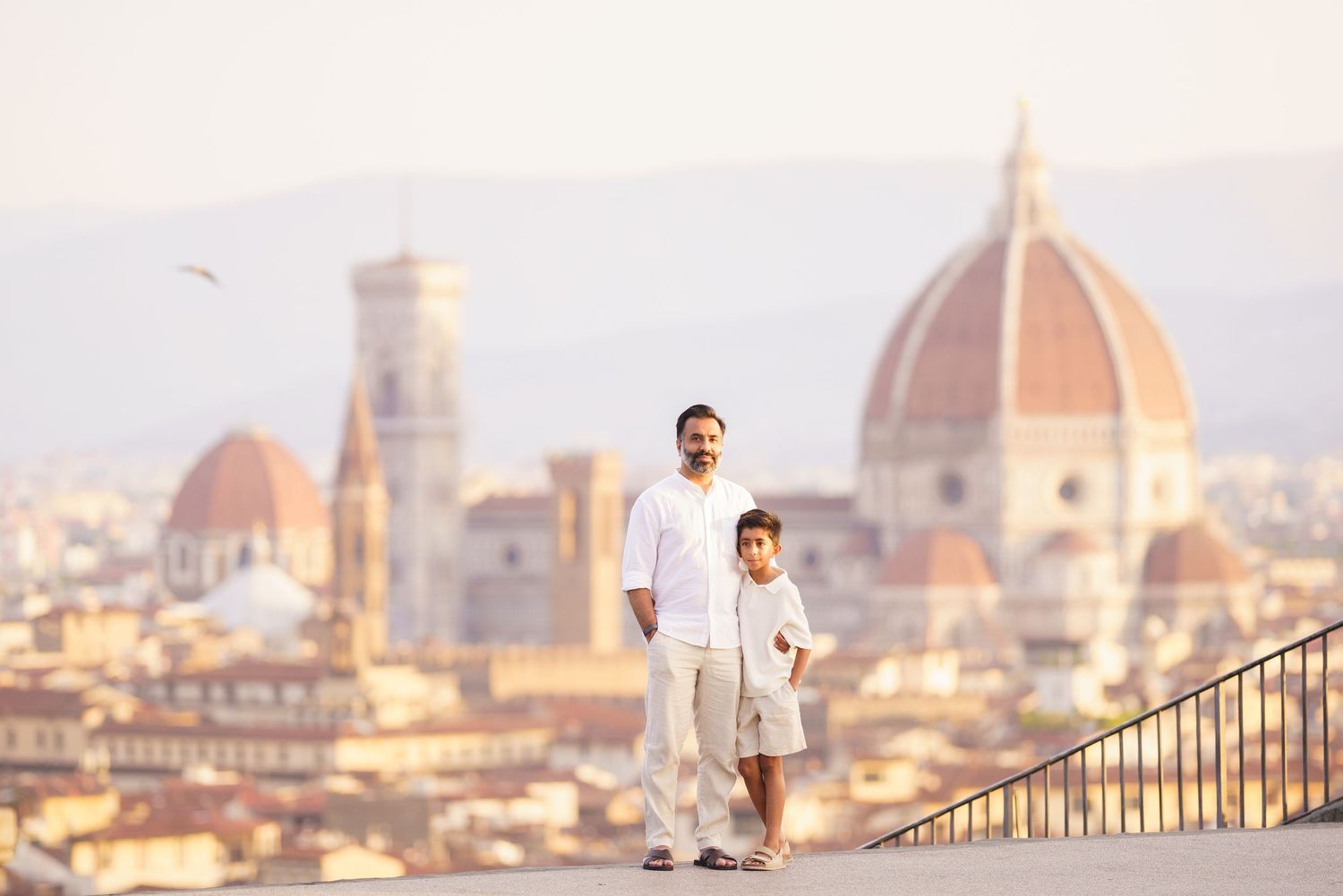 Father and son standing on a terrace with Florence Cathedral dome and cityscape in the background.
