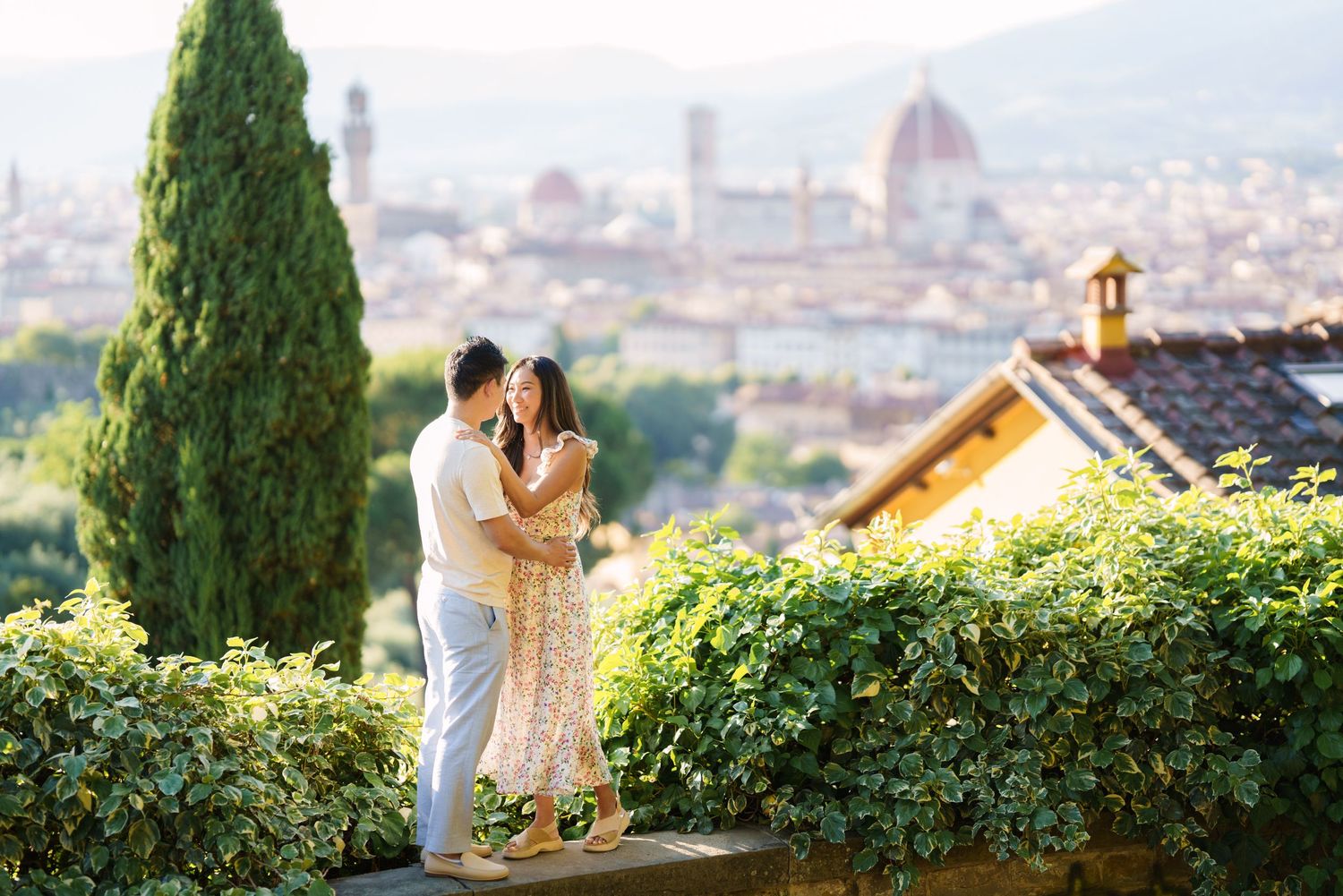 Romantic couple embracing at Piazzale Michelangelo with Florence skyline and Duomo cathedral in background.