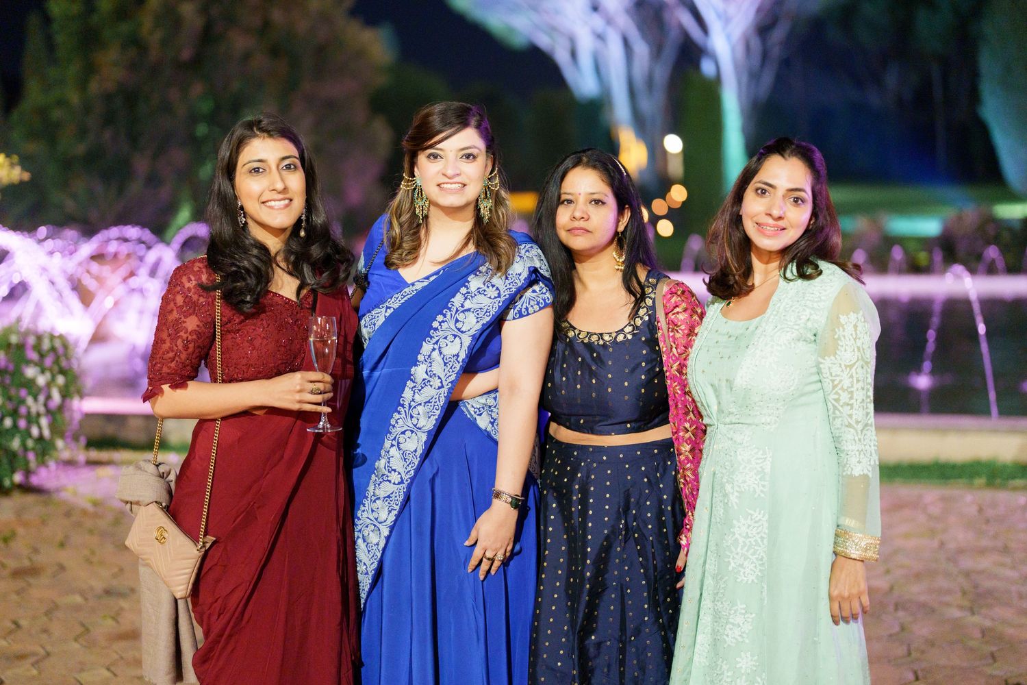 Group photo of party guests wearing colorful formal attire at an outdoor celebration.