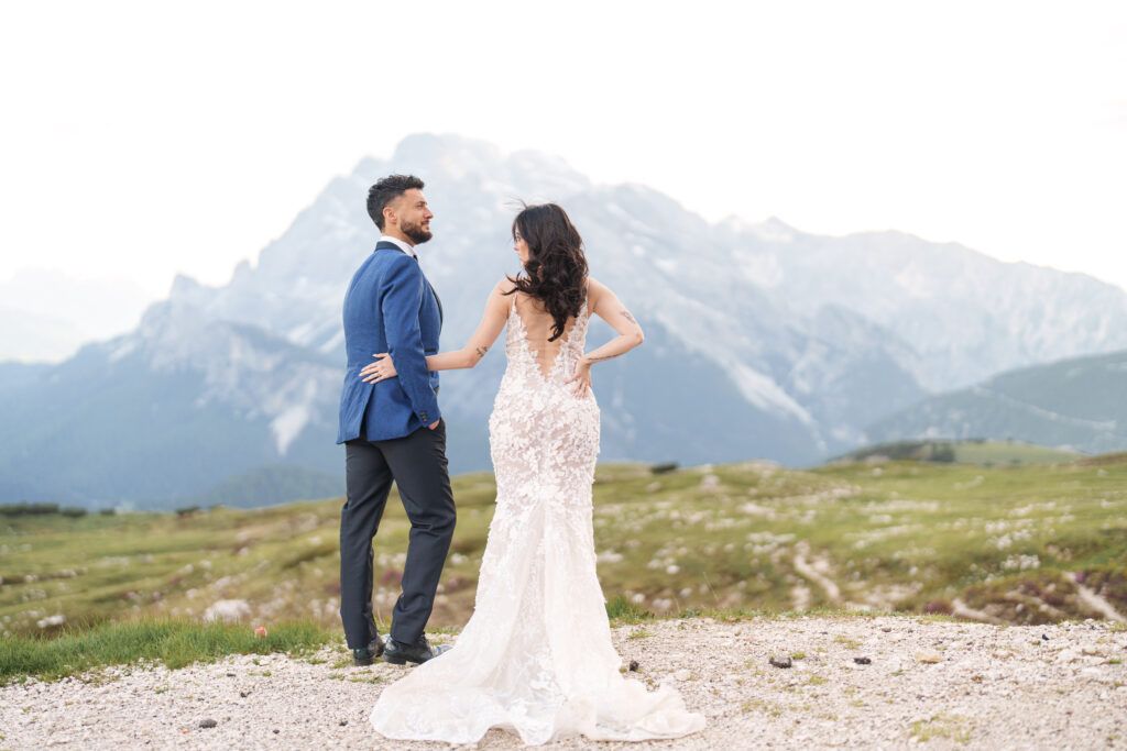 A couple poses for wedding photos against stunning mountain scenery in the Italian Dolomites.