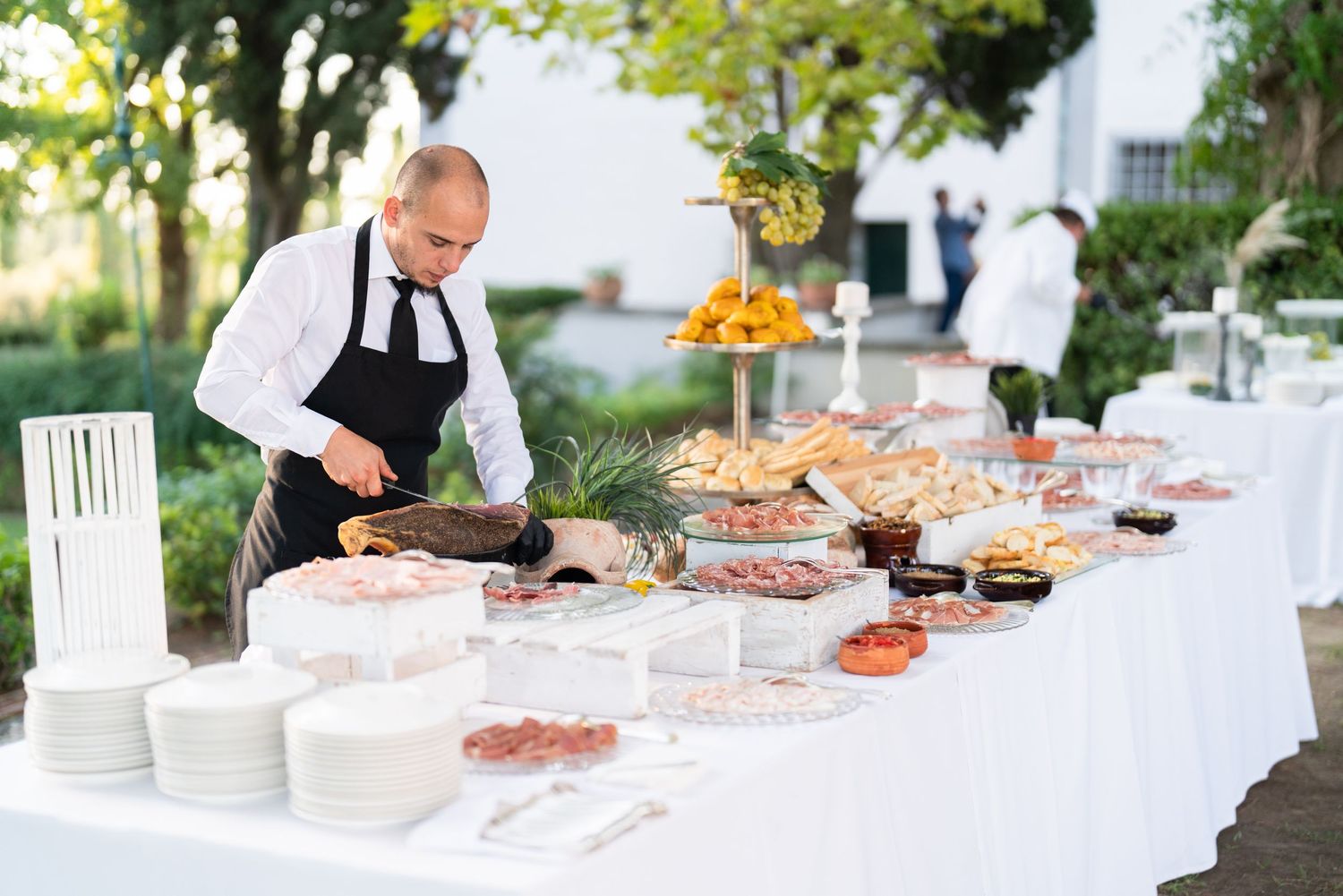 A catering display featuring an elegant spread of appetizers and dishes on a white tablecloth.