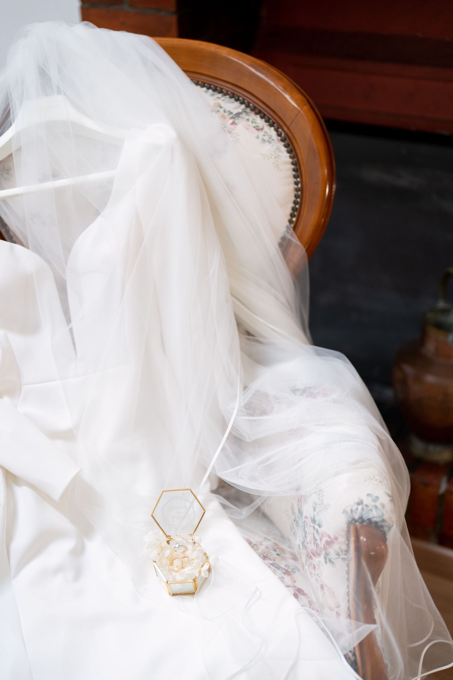 Close-up detail of delicate white wedding veil with hexagonal gold accent piece.