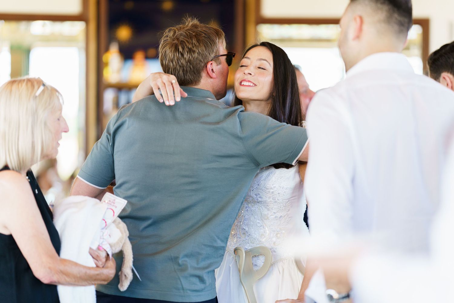 Guests sharing warm embraces during a celebratory indoor gathering.