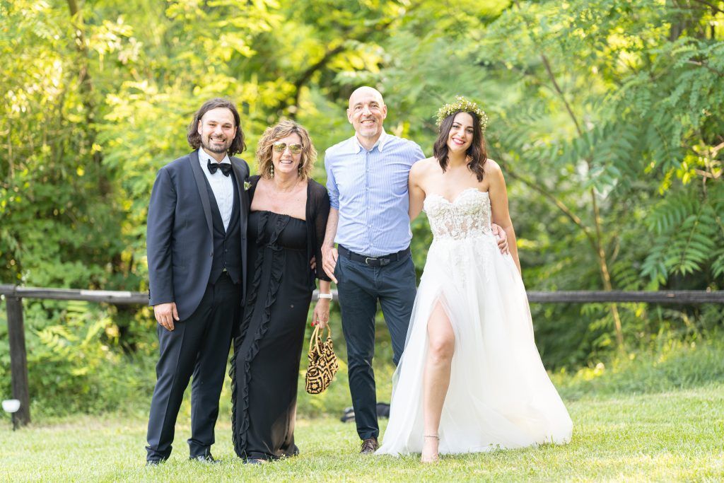 Wedding party walking and mingling on landscaped grounds near modern venue.