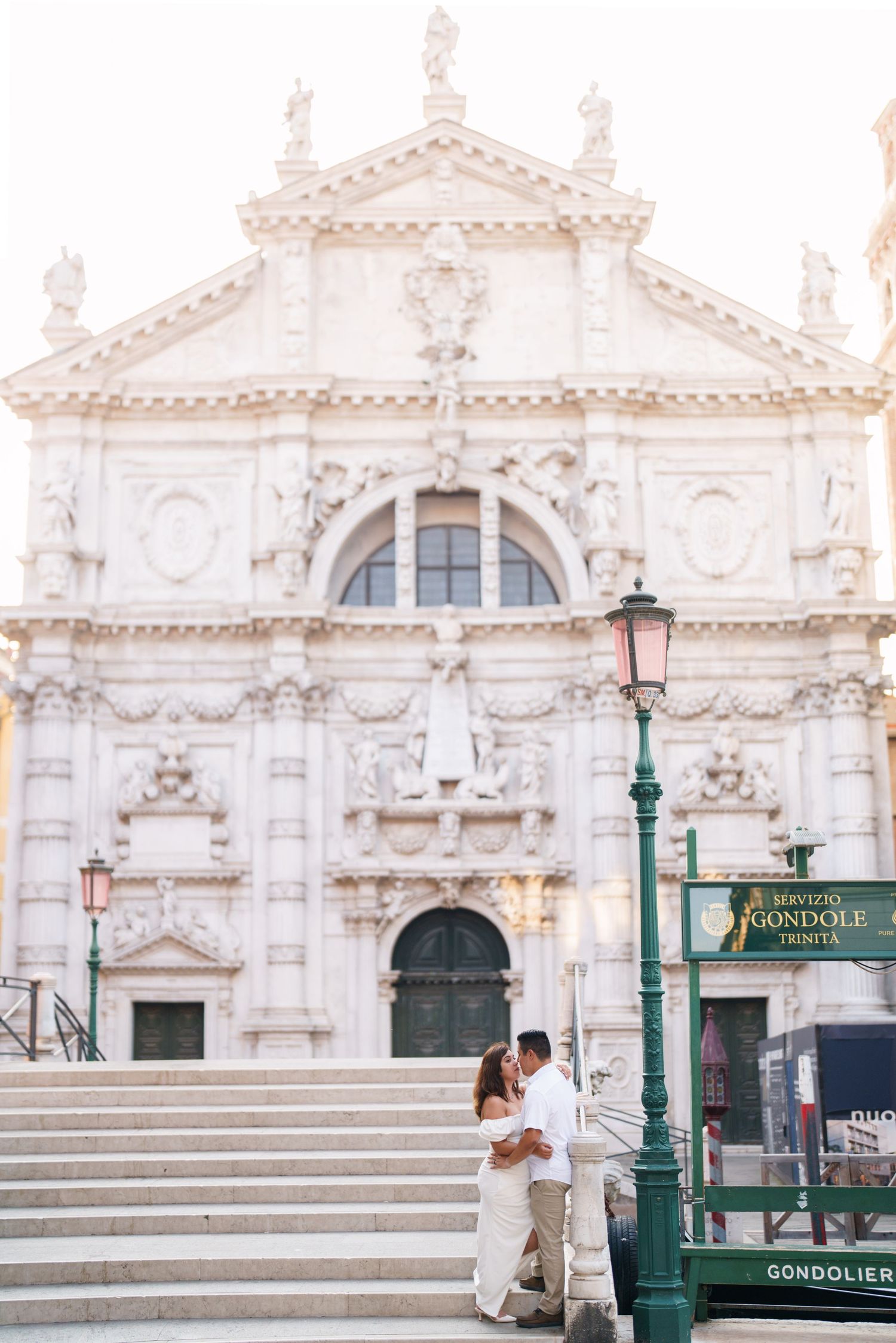 Elegant white marble steps and ornate Baroque architecture of St. Mark's Basilica in Venice with gondola station sign.