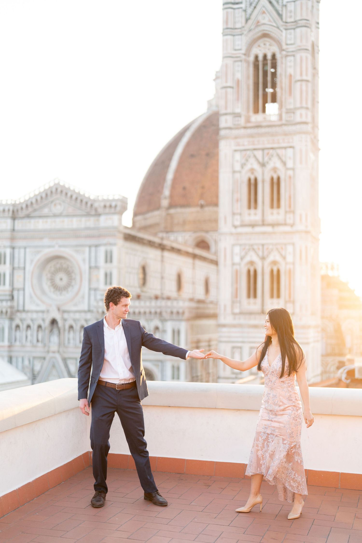 A romantic couple dances together at sunset on a rooftop terrace overlooking the Florence Cathedral in Italy.