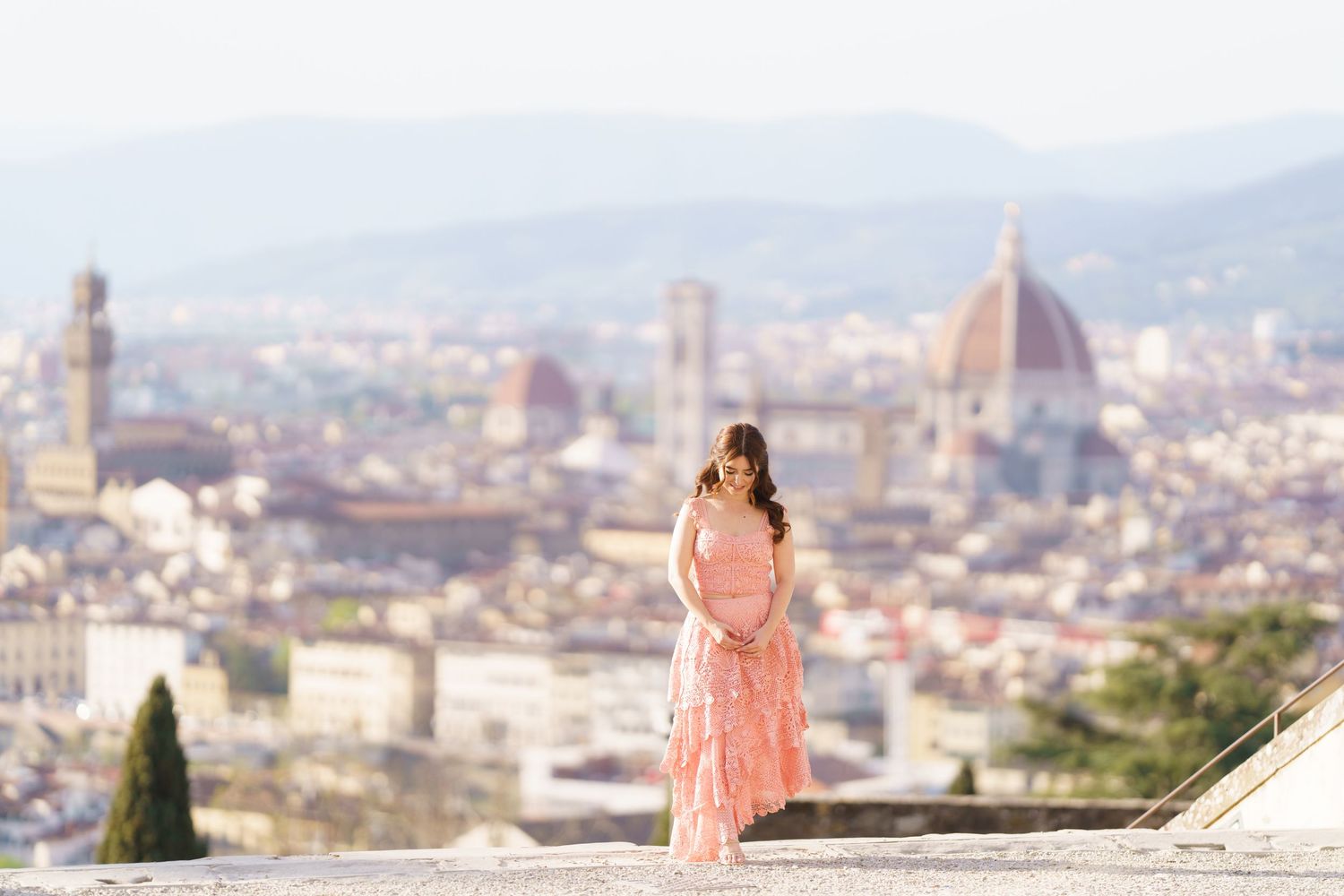 Person in a pink dress admires the stunning cityscape of Florence, Italy with the Duomo cathedral in the background.