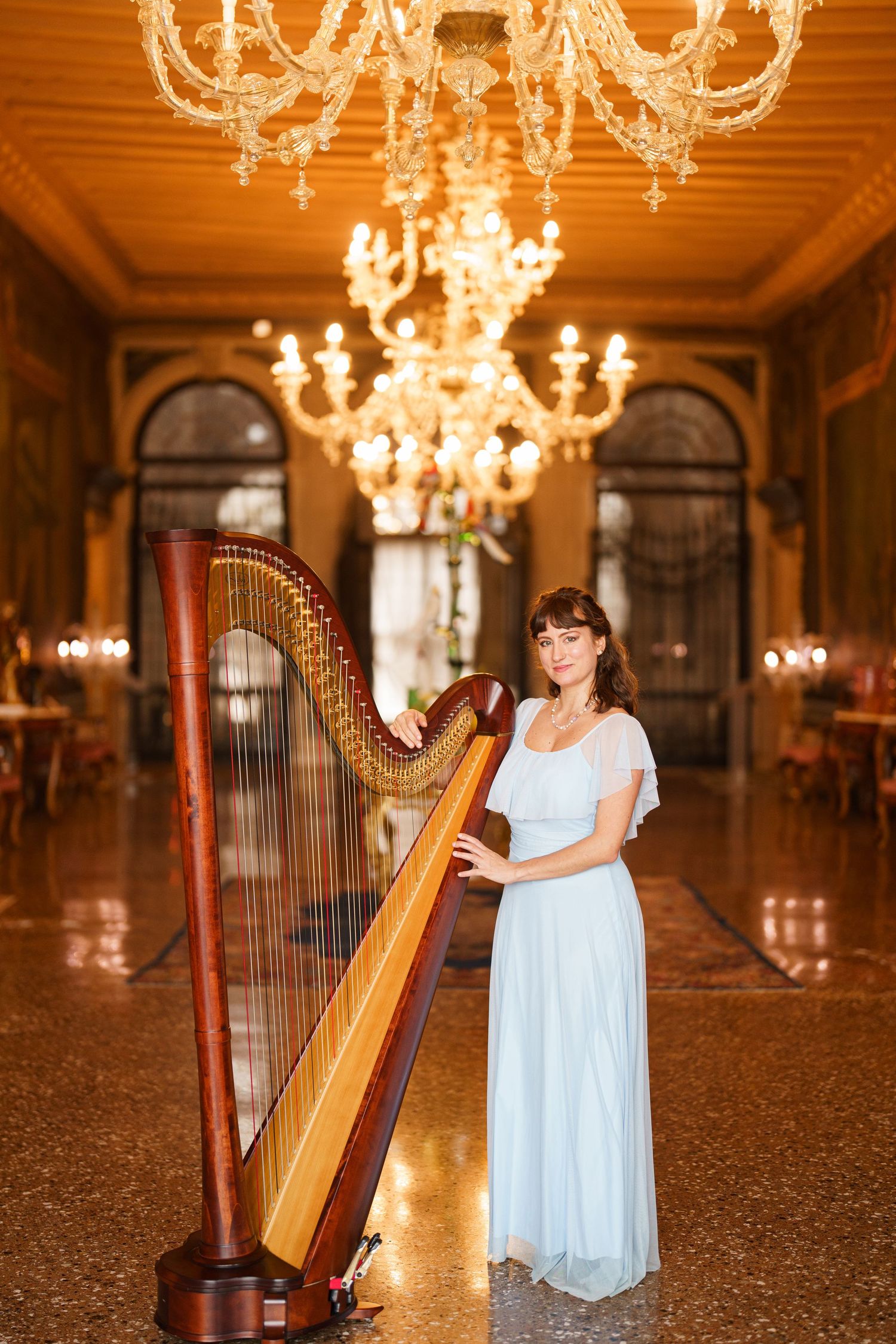 Elegant harp performance in a grand ballroom with crystal chandeliers and ornate decor.