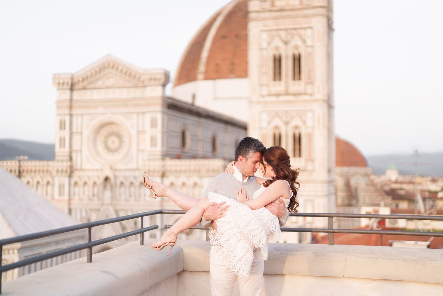 A romantic couple embraces on a rooftop terrace overlooking the Florence Cathedral and Duomo in Italy.