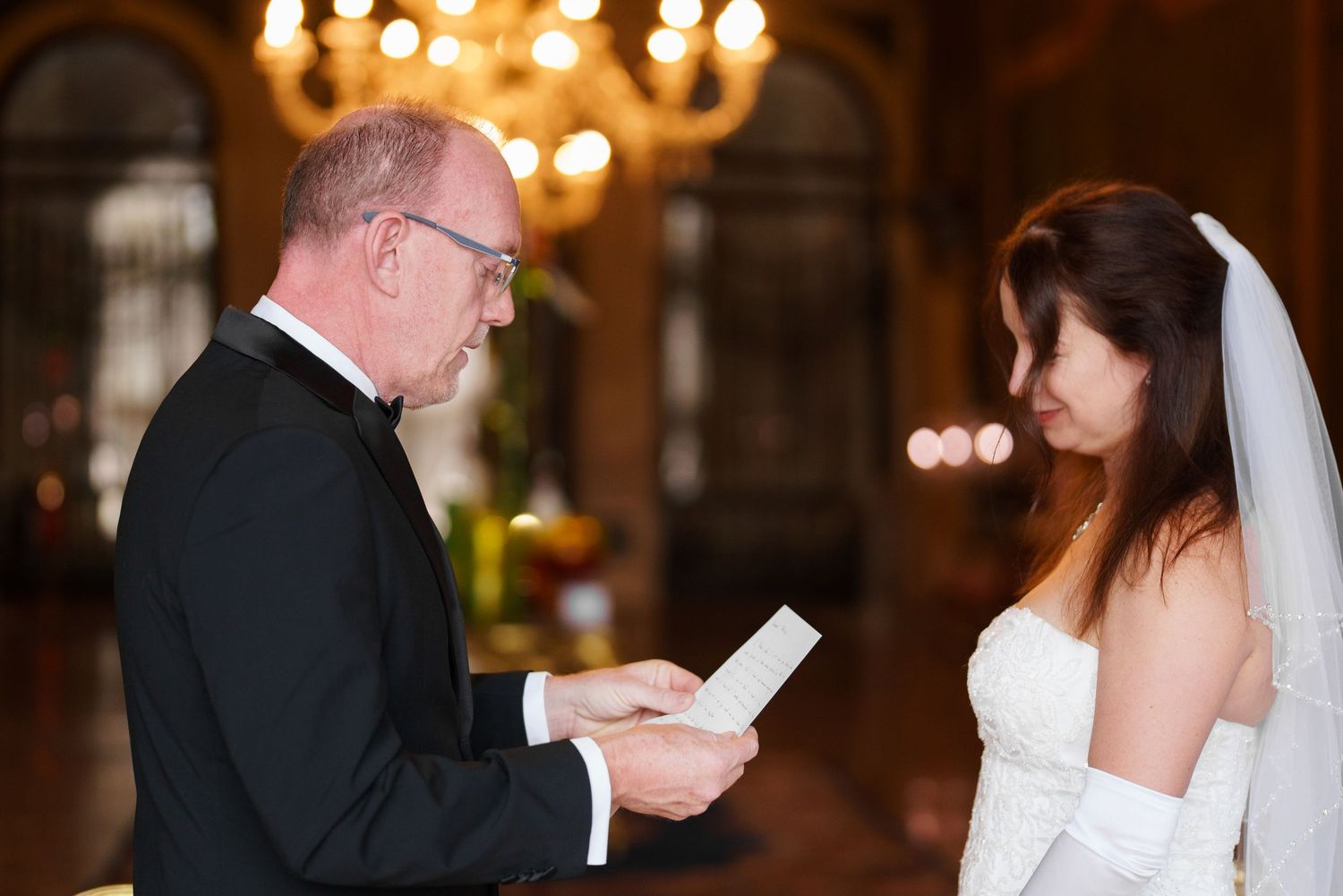 A sequence of wedding ceremony moments showing vows and ring exchanges in an elegant chandelier-lit venue.