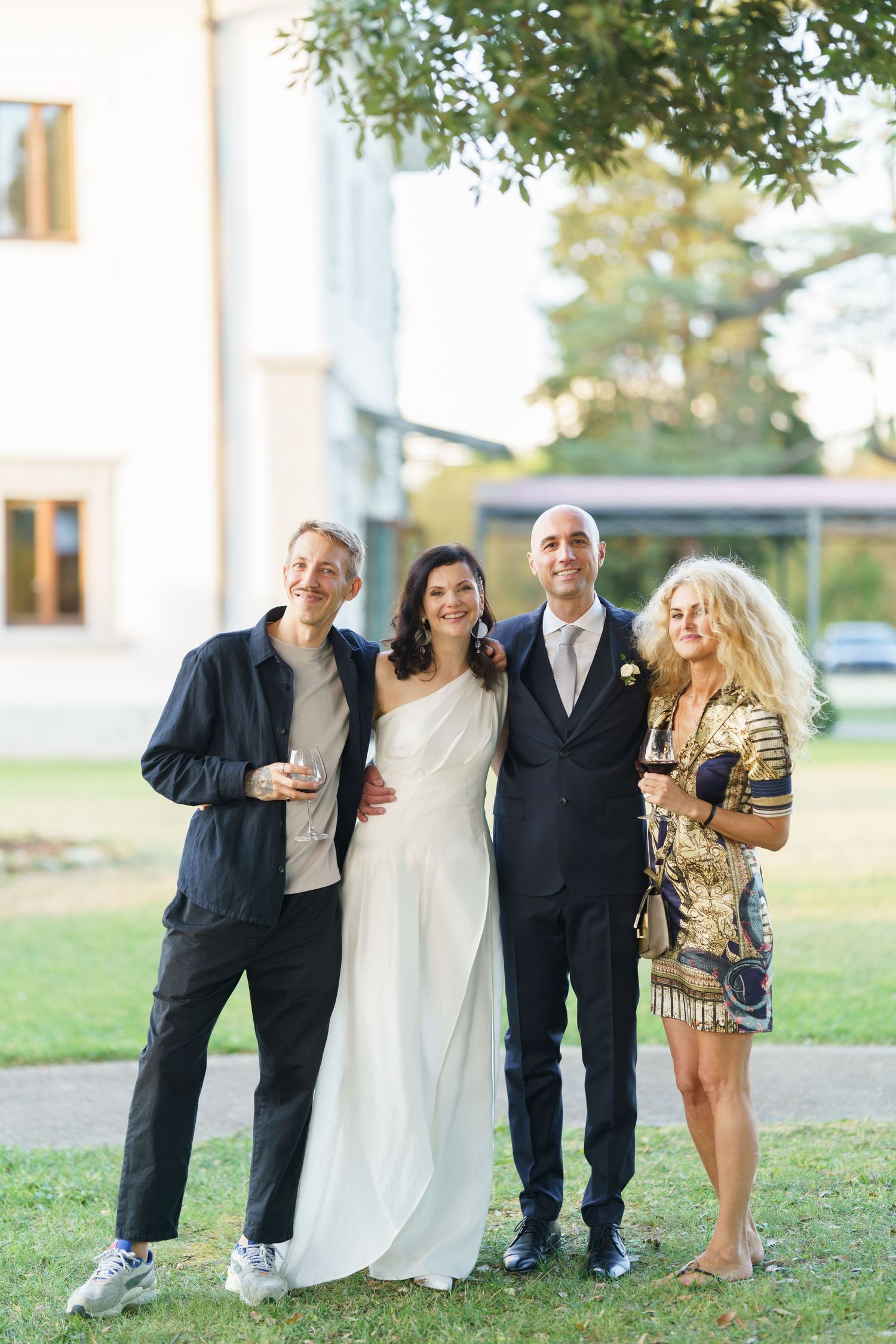Wedding group poses casually on lawn in mix of formal and casual attire.