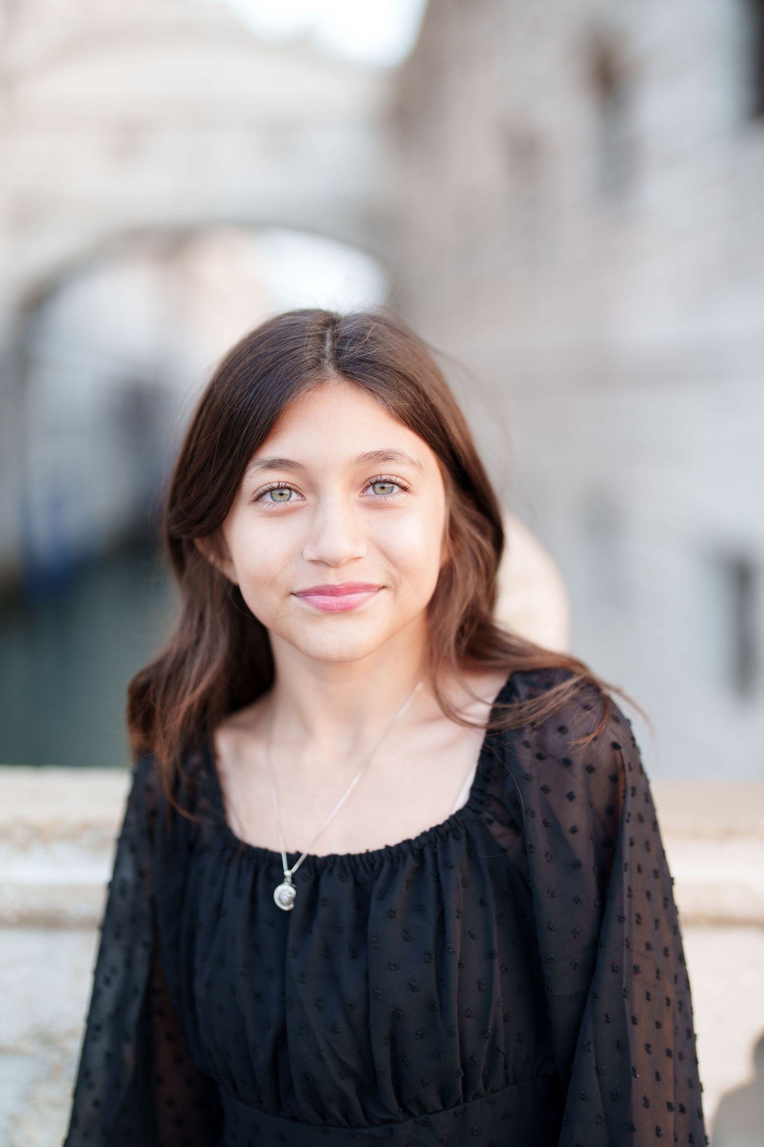 A person wearing a black polka dot blouse smiles warmly in a series of four connected portrait photos.