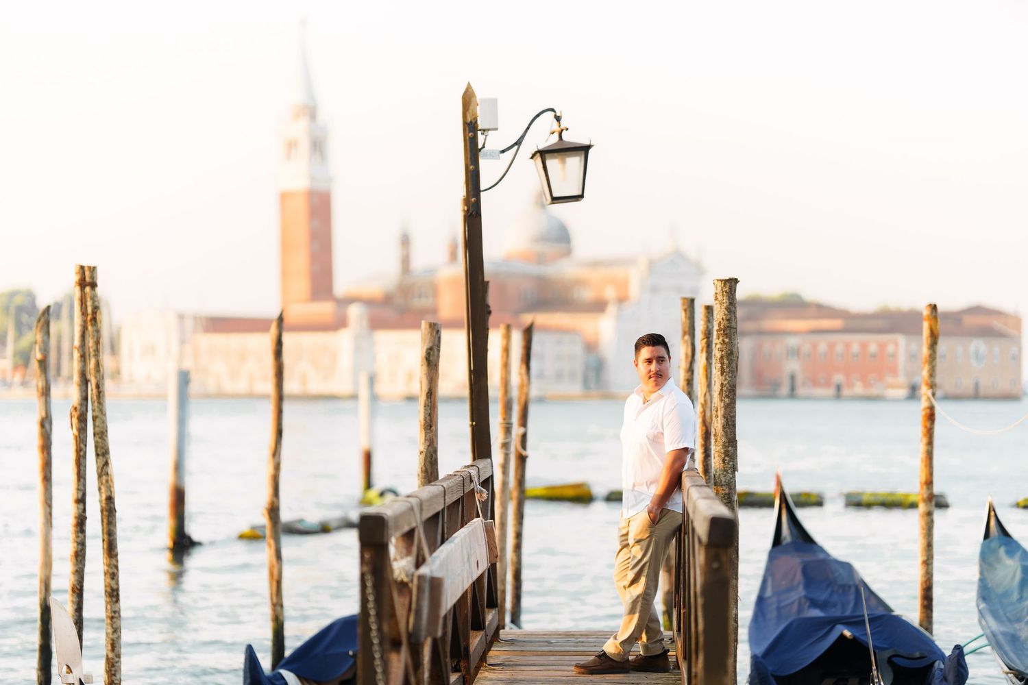 photographer venice A scenic view of Venice's Grand Canal at sunset with wooden posts and gondolas in the water.