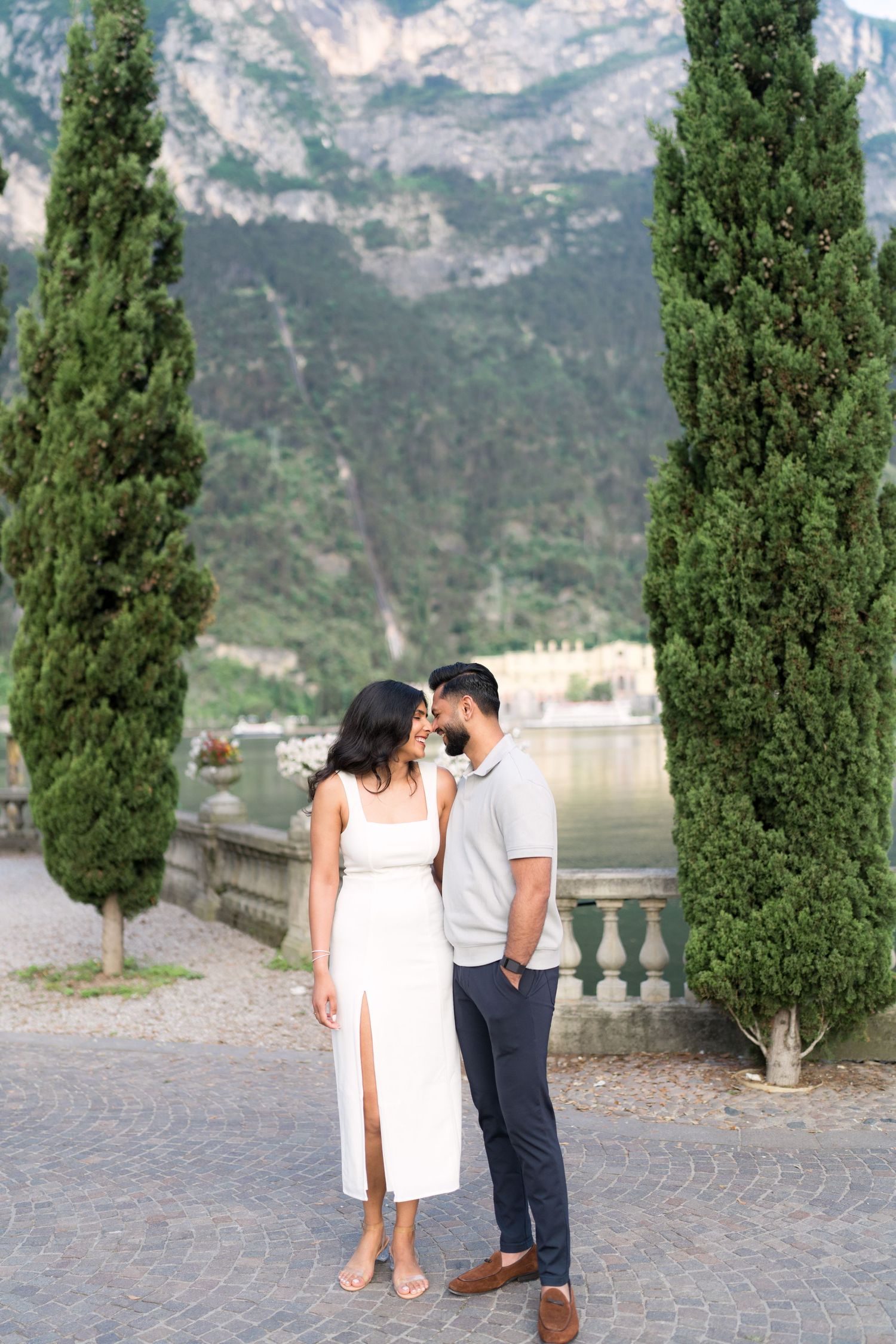A couple shares a romantic moment on a stone terrace overlooking scenic mountain views in Lake Como, Italy.