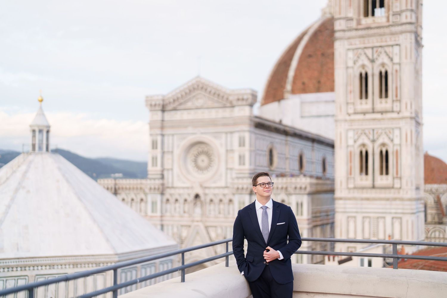 Wedding couple poses on rooftop terrace overlooking Florence Cathedral and historic cityscape in Italy.