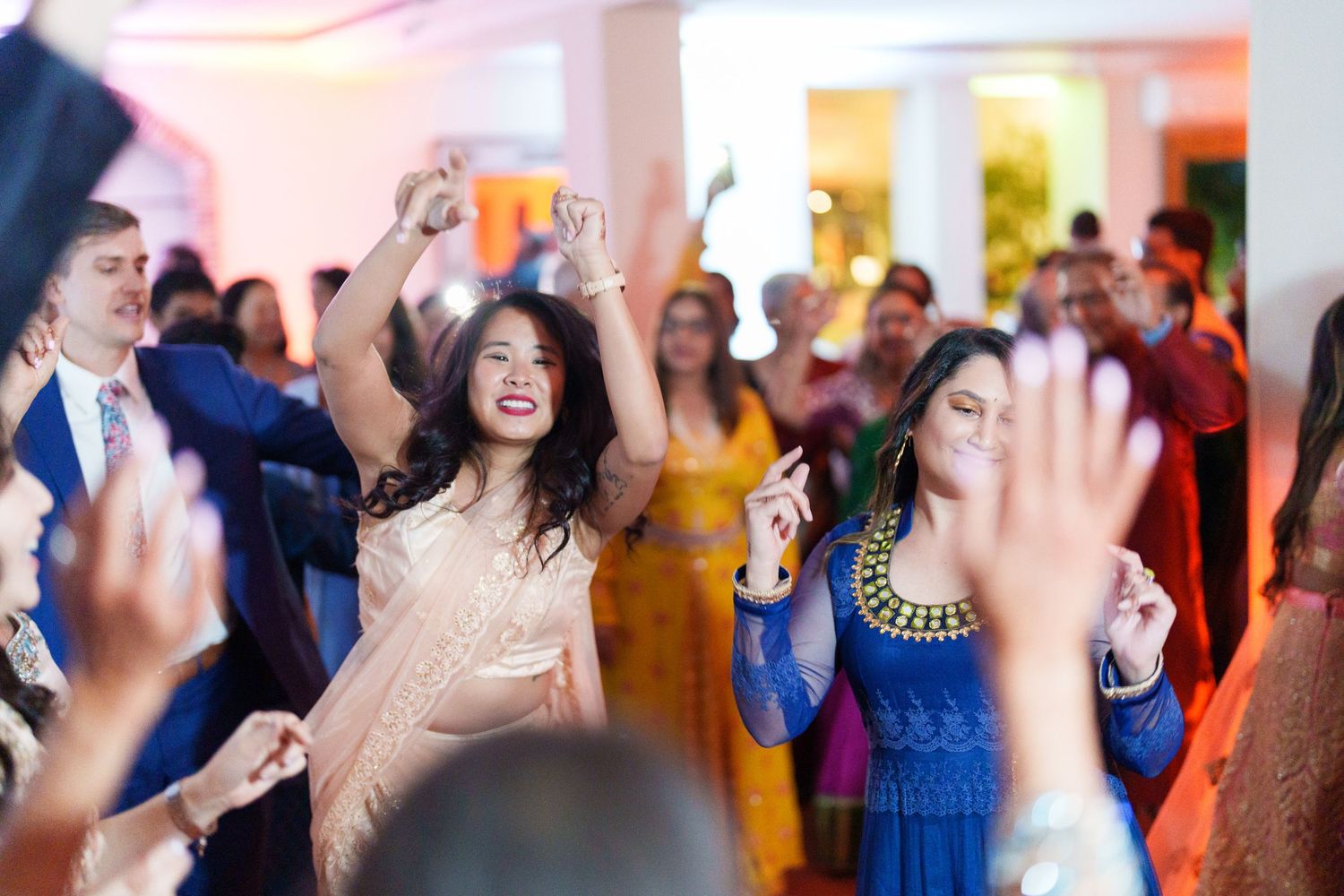 Joyful guests dance and celebrate at a vibrant wedding reception with colorful traditional attire.