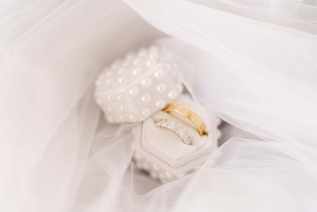 White wedding accessories including gloves and jewelry arranged on light fabric.