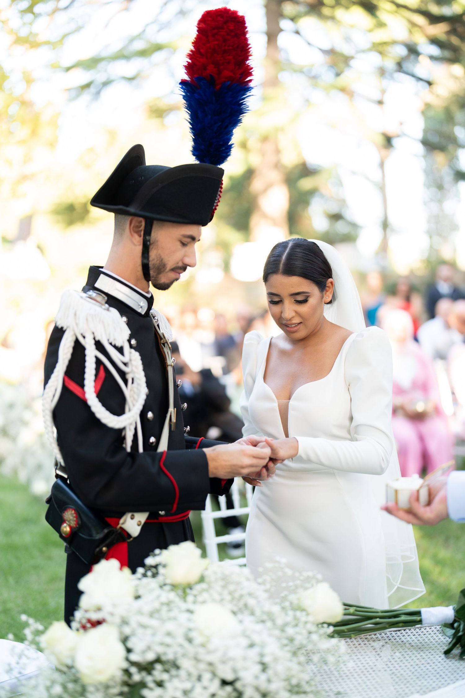 Military ceremonial guards in formal uniforms participate in wedding ceremony with white floral decorations.