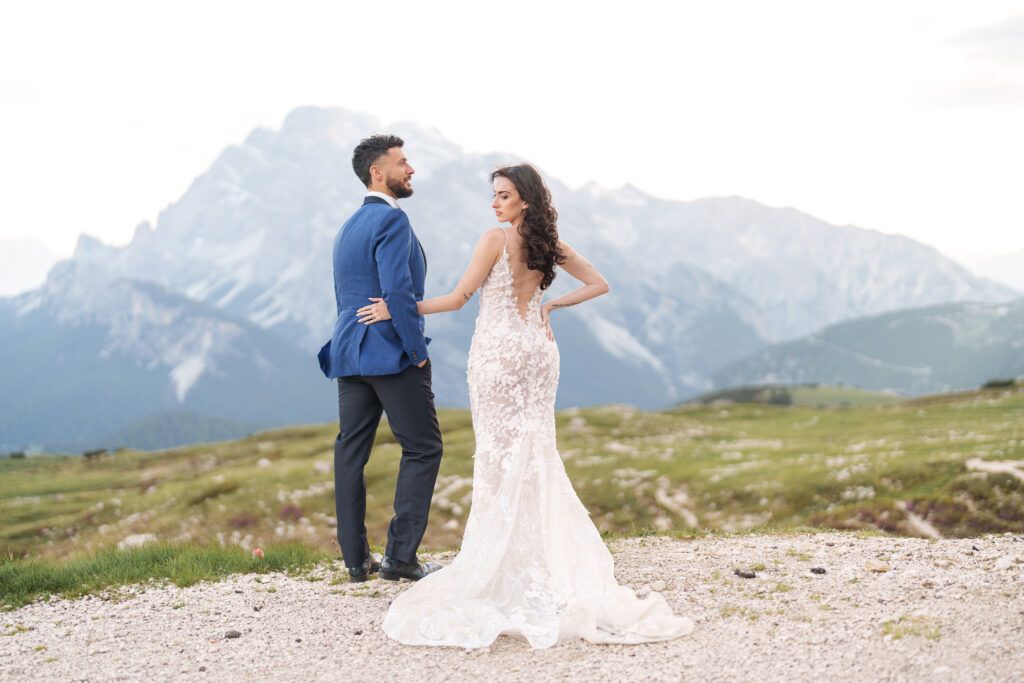 Newlyweds pose together on a scenic mountain ridge with sweeping views of the Dolomites.