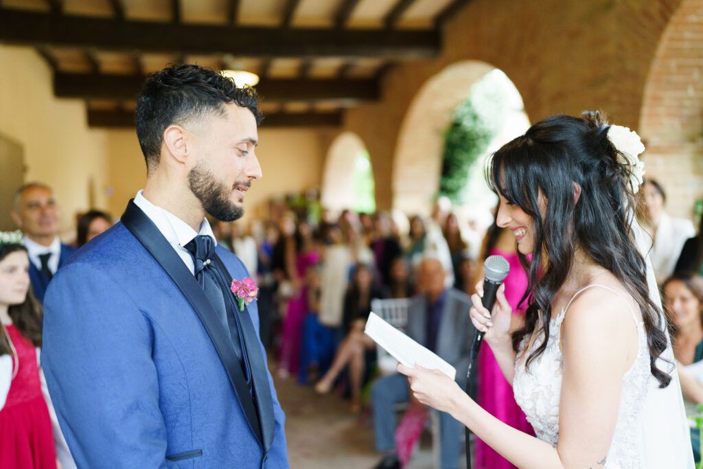 Couple exchanges vows during wedding ceremony under rustic wooden beams.