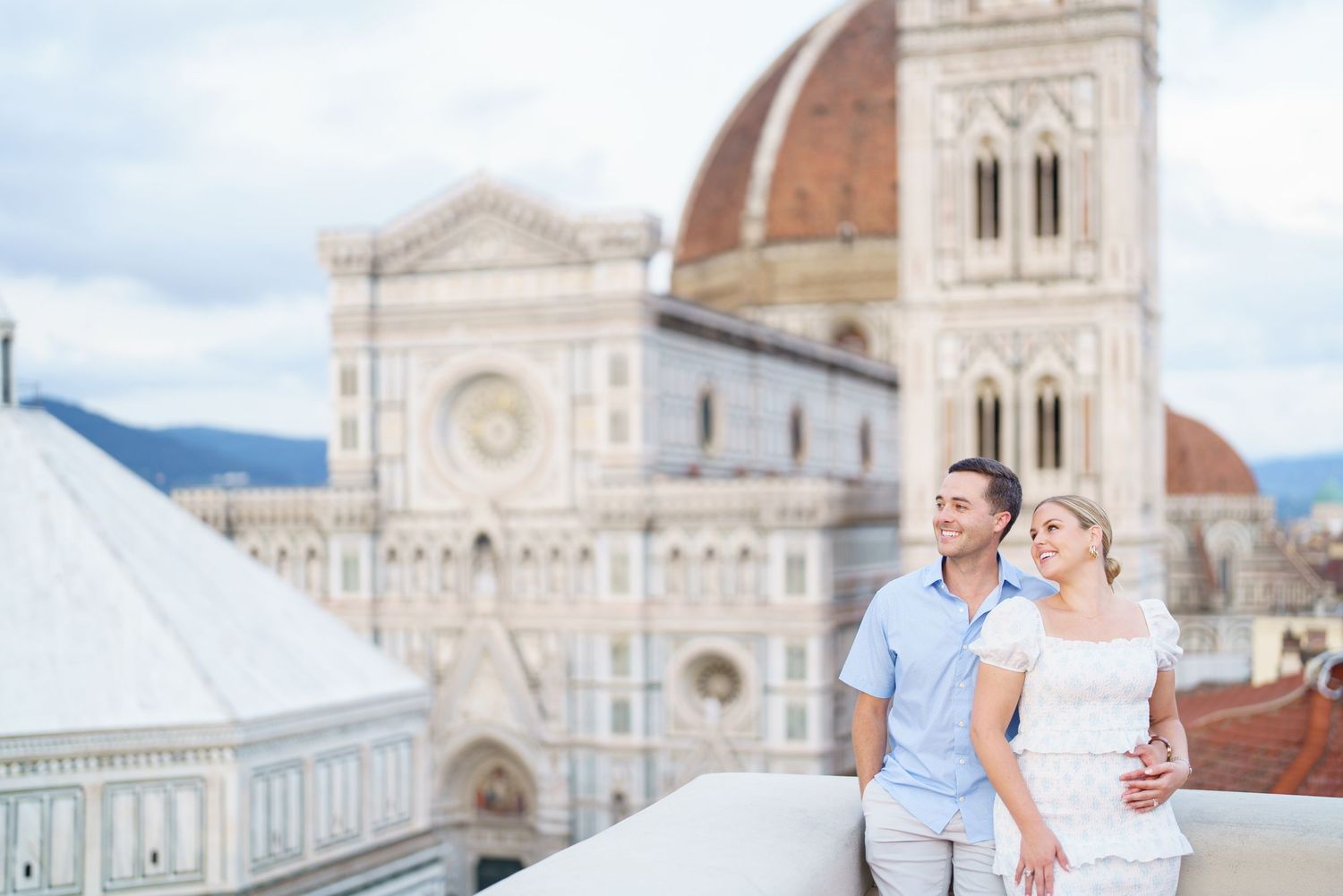 A couple embraces in front of the Florence Cathedral and Duomo with its iconic Renaissance architecture in Italy.