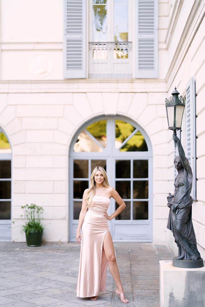 Elegant evening gown photo at luxurious venue with ornate architecture and decorative statue.