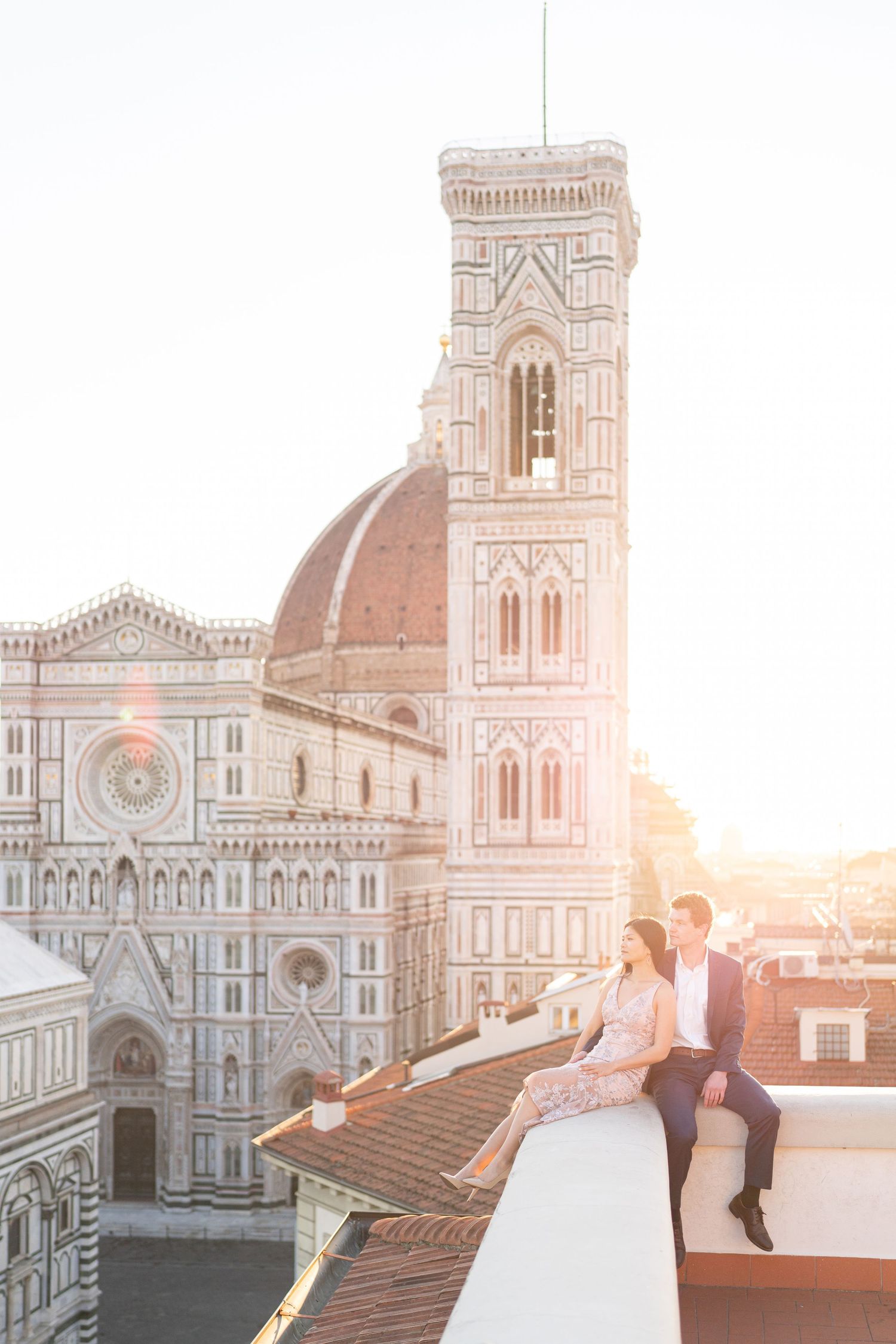 Romantic couple in formal attire embracing at sunset in front of Florence Cathedral's iconic dome and architecture.