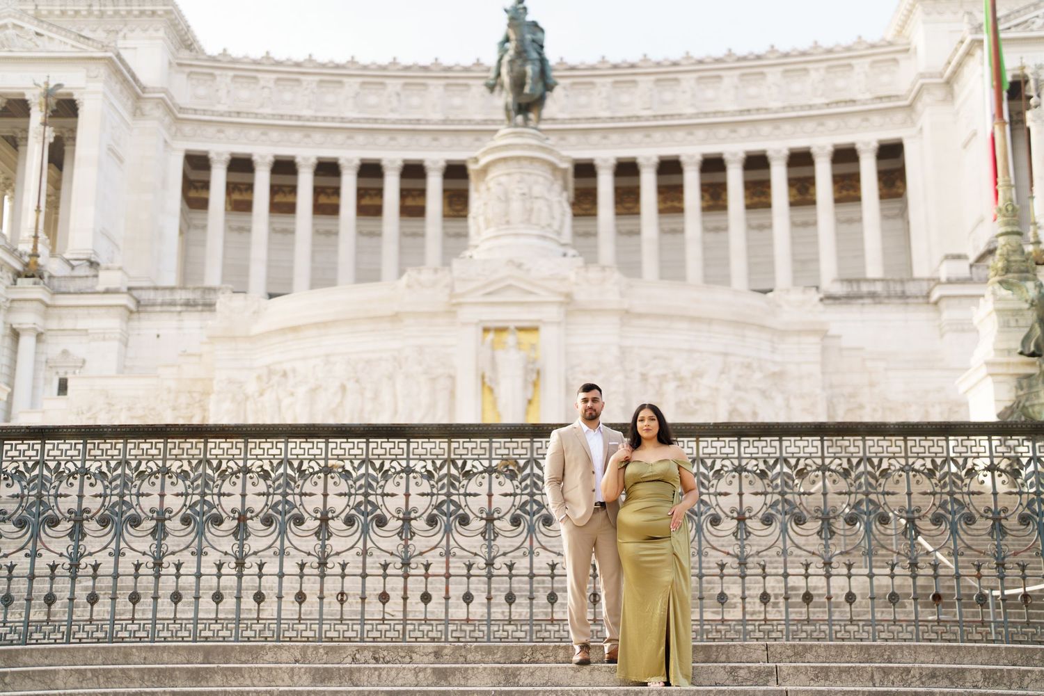 Couple posing in front of the Altare della Patria monument in Rome, Italy, dressed in elegant attire.