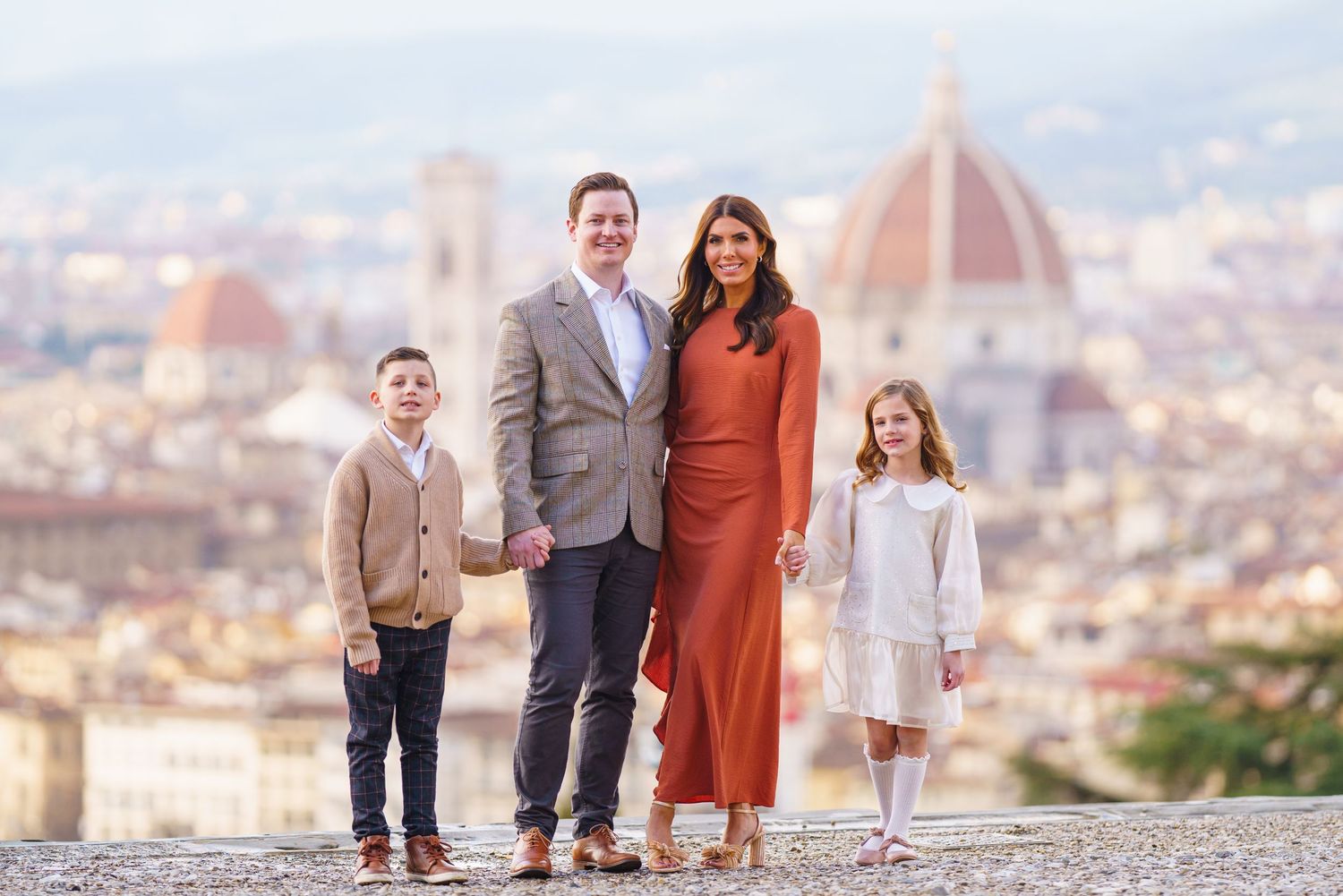 Family of four posing in front of Florence Cathedral and city skyline, dressed in elegant attire.