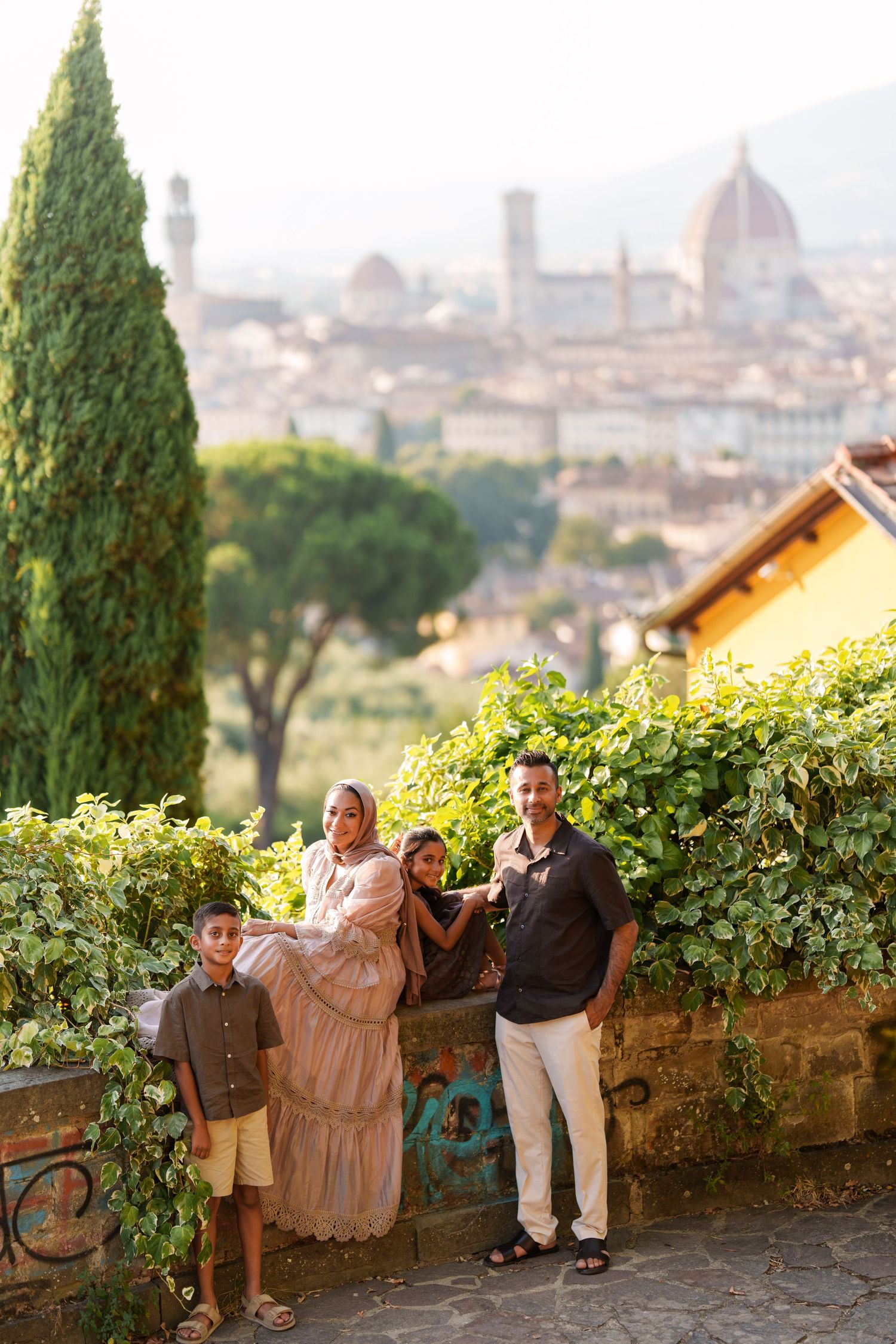 Family of four posing at Piazzale Michelangelo with Florence skyline and Duomo cathedral in background.
