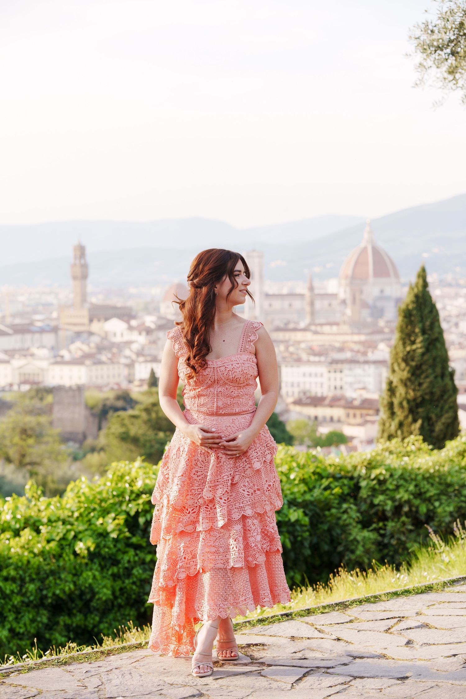 Person in a pink lace dress poses at Piazzale Michelangelo overlooking Florence's iconic Duomo and cityscape.