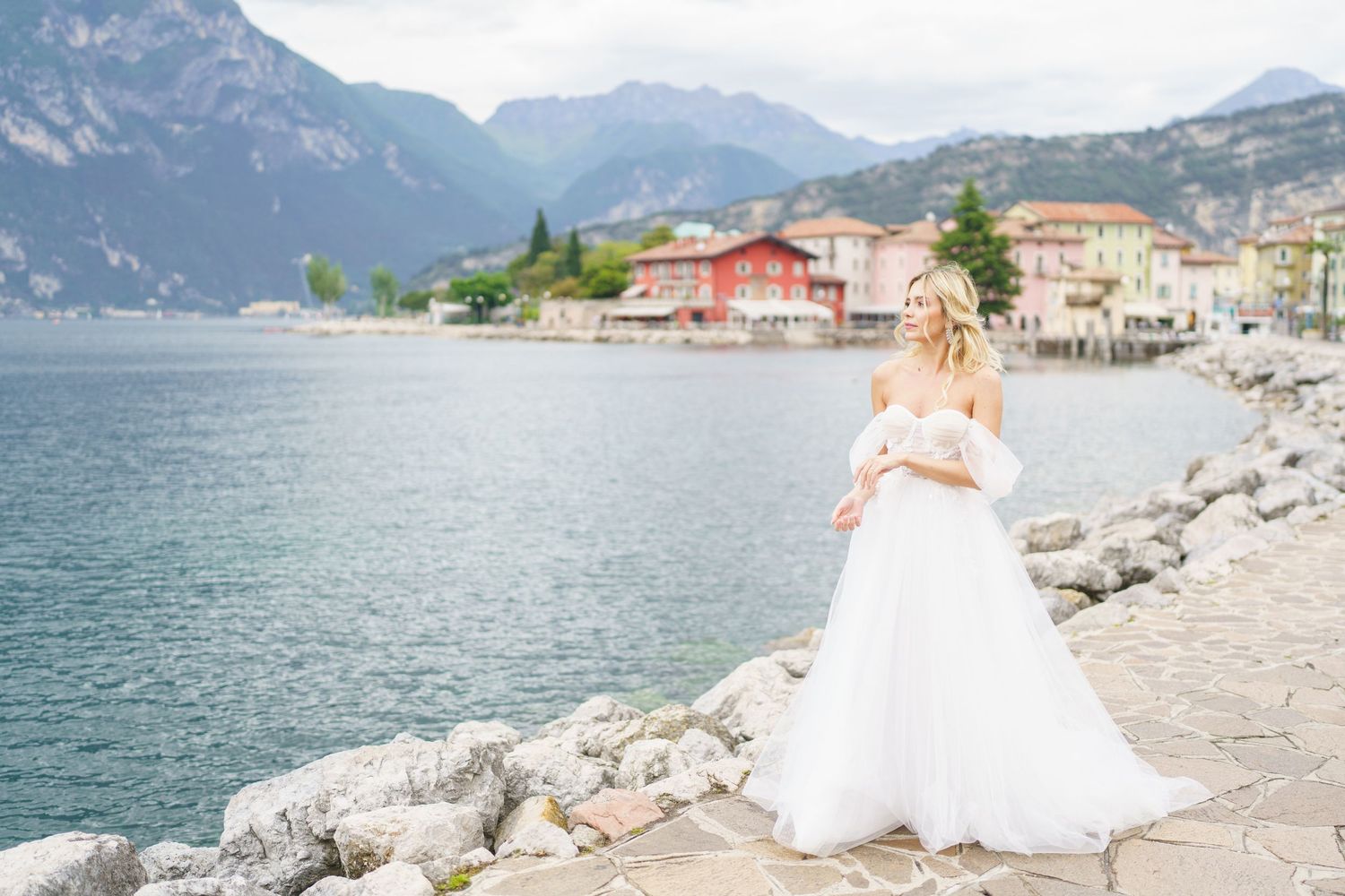 Scenic mountain lake views with rocky shoreline and charming Italian village buildings nestled along Lake Garda.