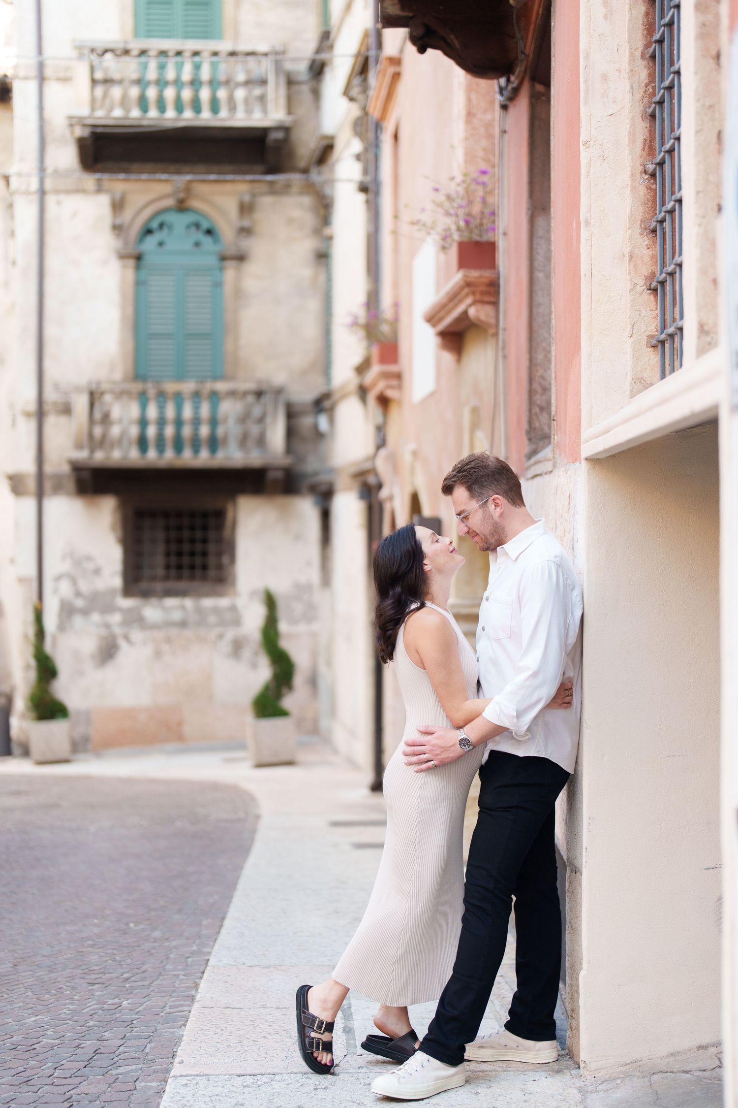 A romantic couple embraces in a series of photos along an elegant European street with ornate architecture.