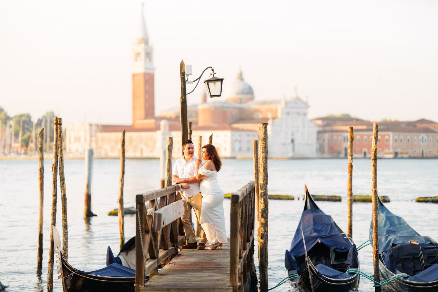 photographer venice Traditional Venetian gondolas moored along wooden posts at sunset with San Giorgio Maggiore church in the background.