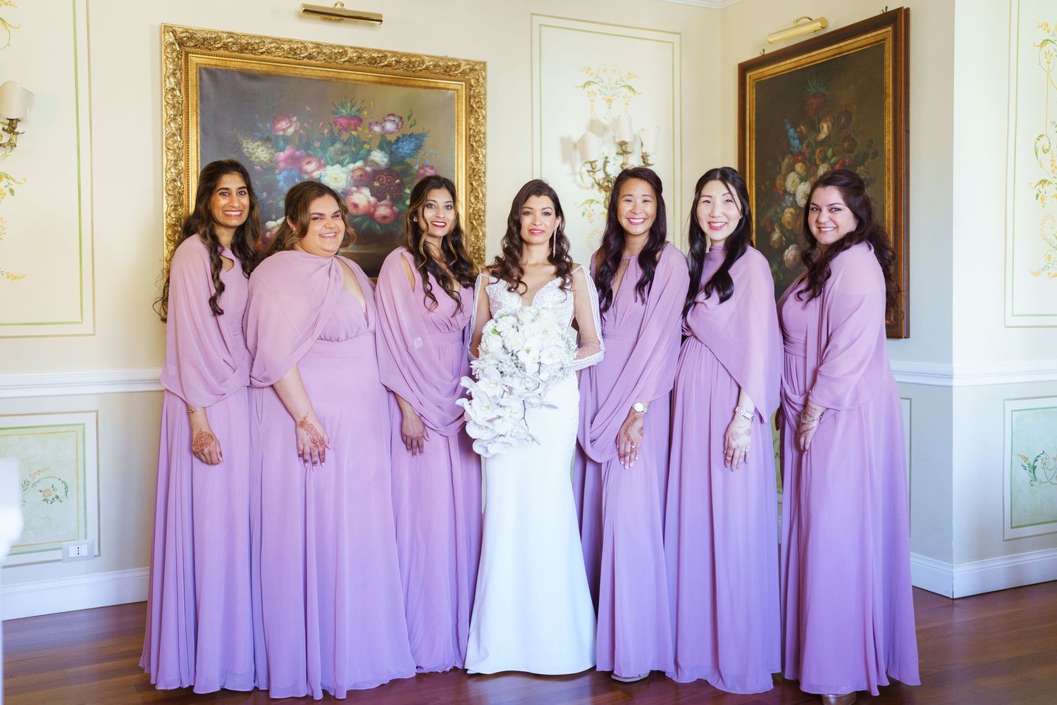 Wedding party poses in formal attire with bridesmaids wearing matching purple gowns.