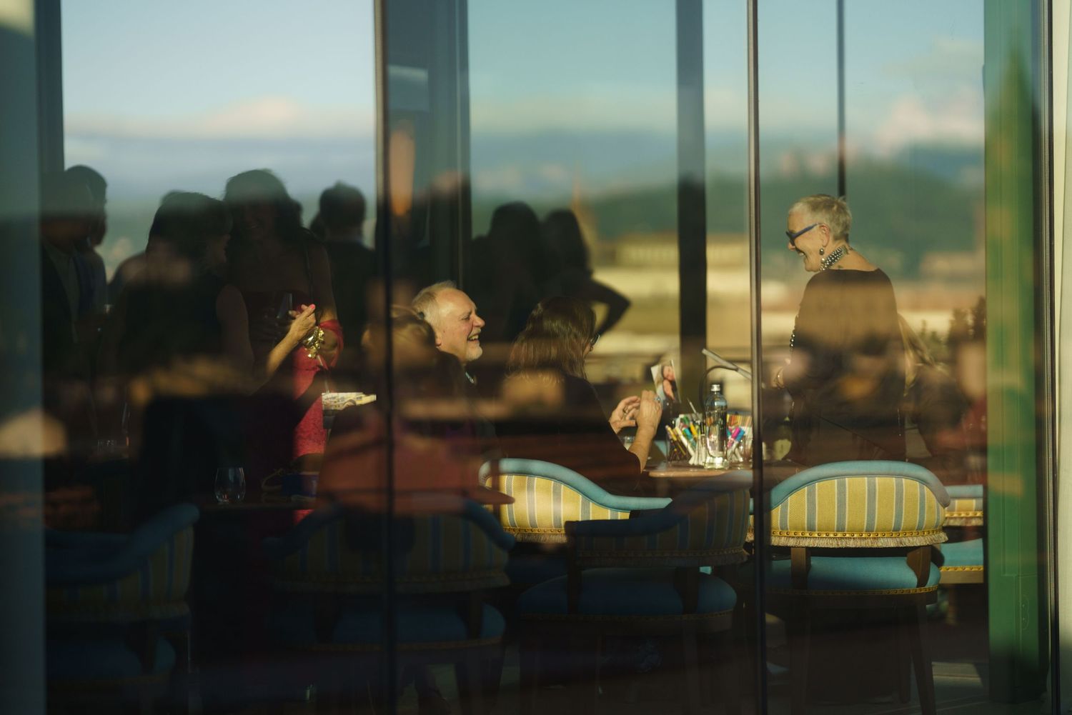 Restaurant diners silhouetted against large windows during sunset creating a moody atmospheric scene.