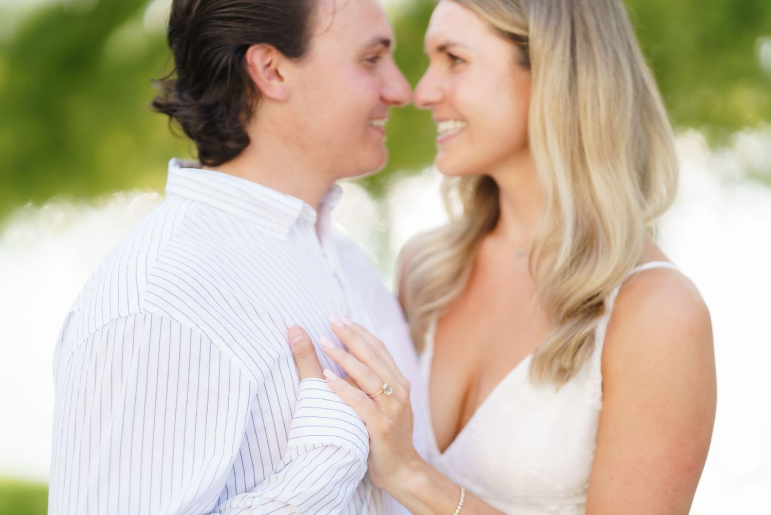 A couple shares romantic moments in a garden setting wearing white and light colored clothing during a photo session.