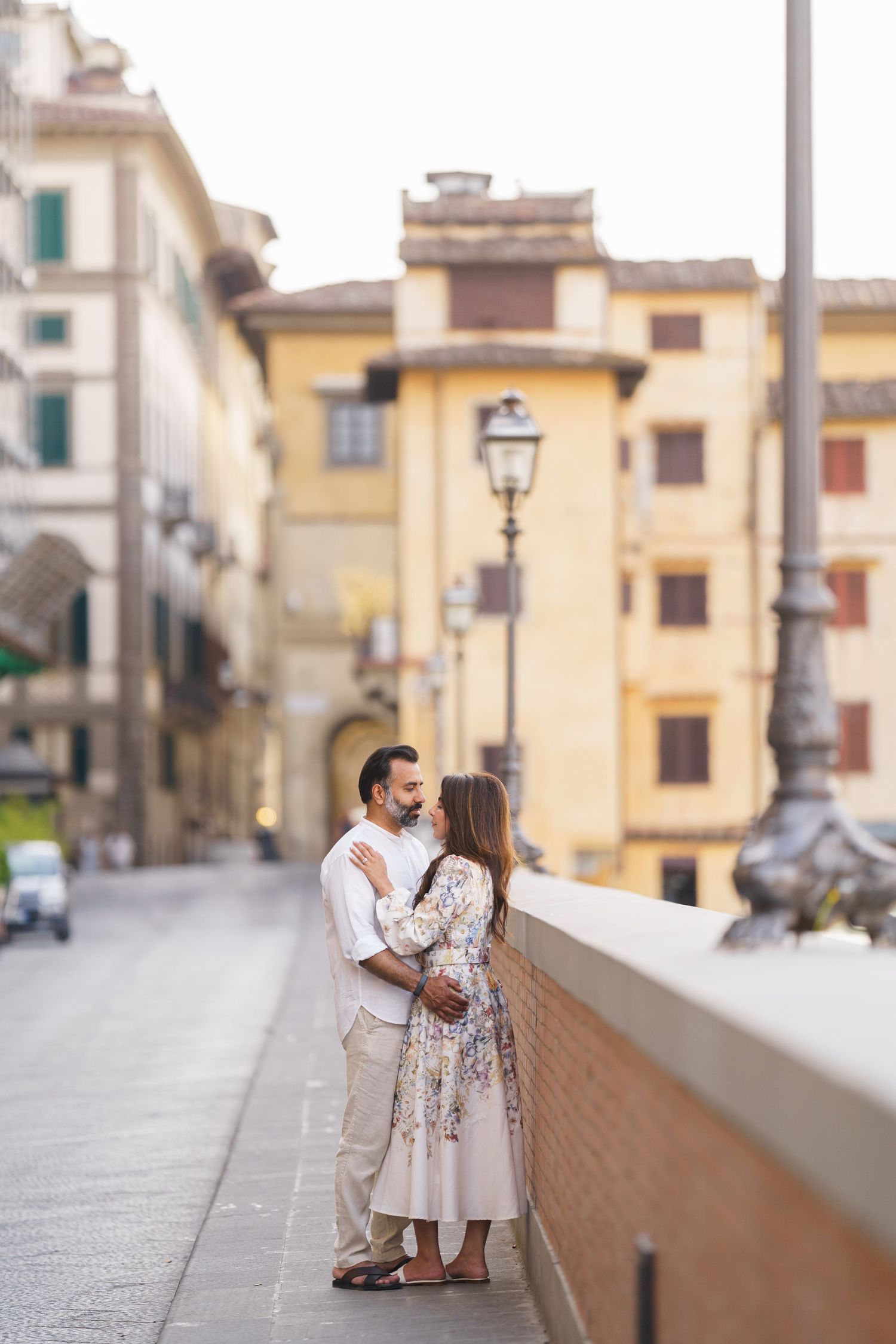 Romantic couple embracing on a cobblestone street in Florence, Italy, surrounded by historic architecture.