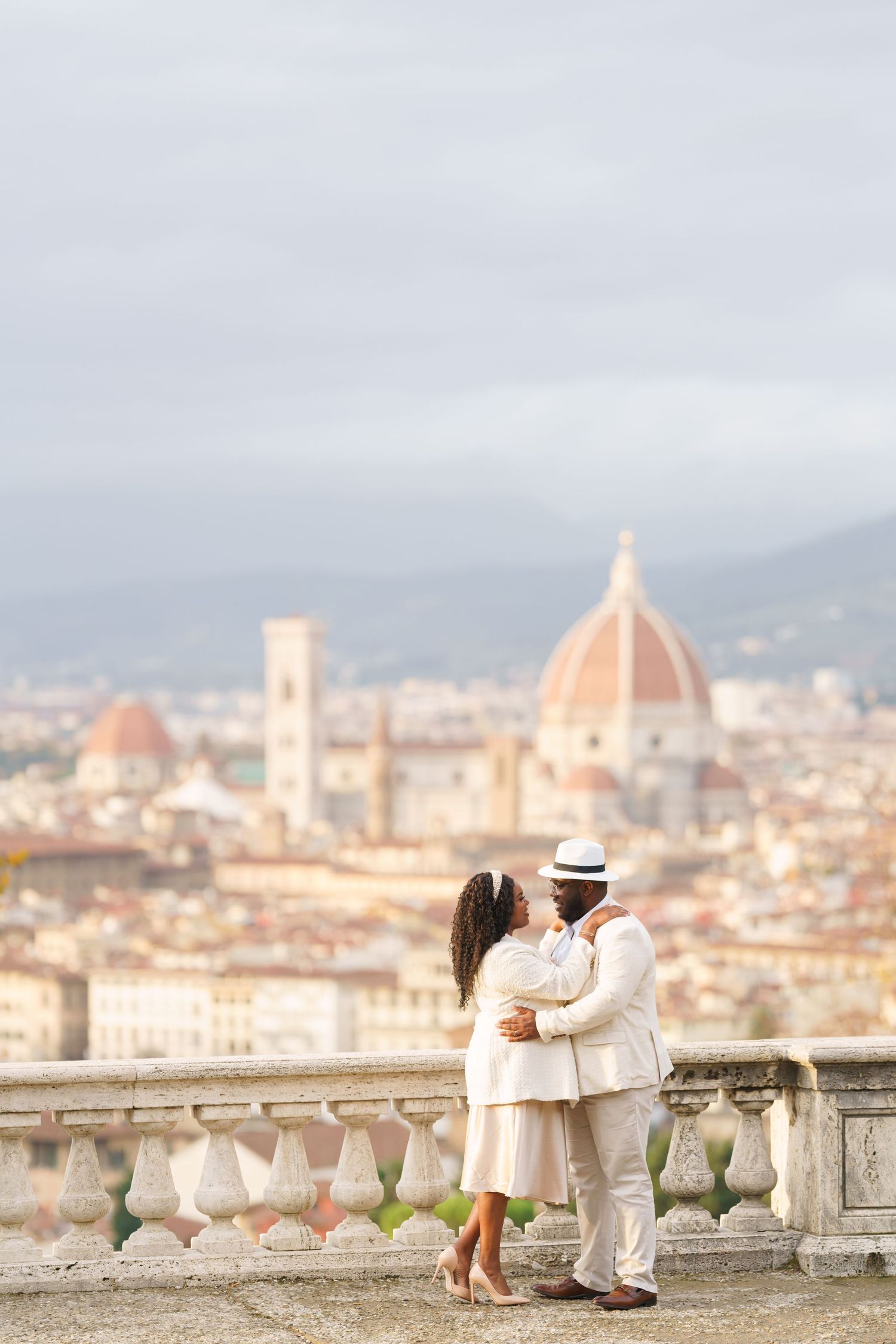Romantic couple embracing on a terrace overlooking Florence skyline with the iconic Duomo cathedral in the background.