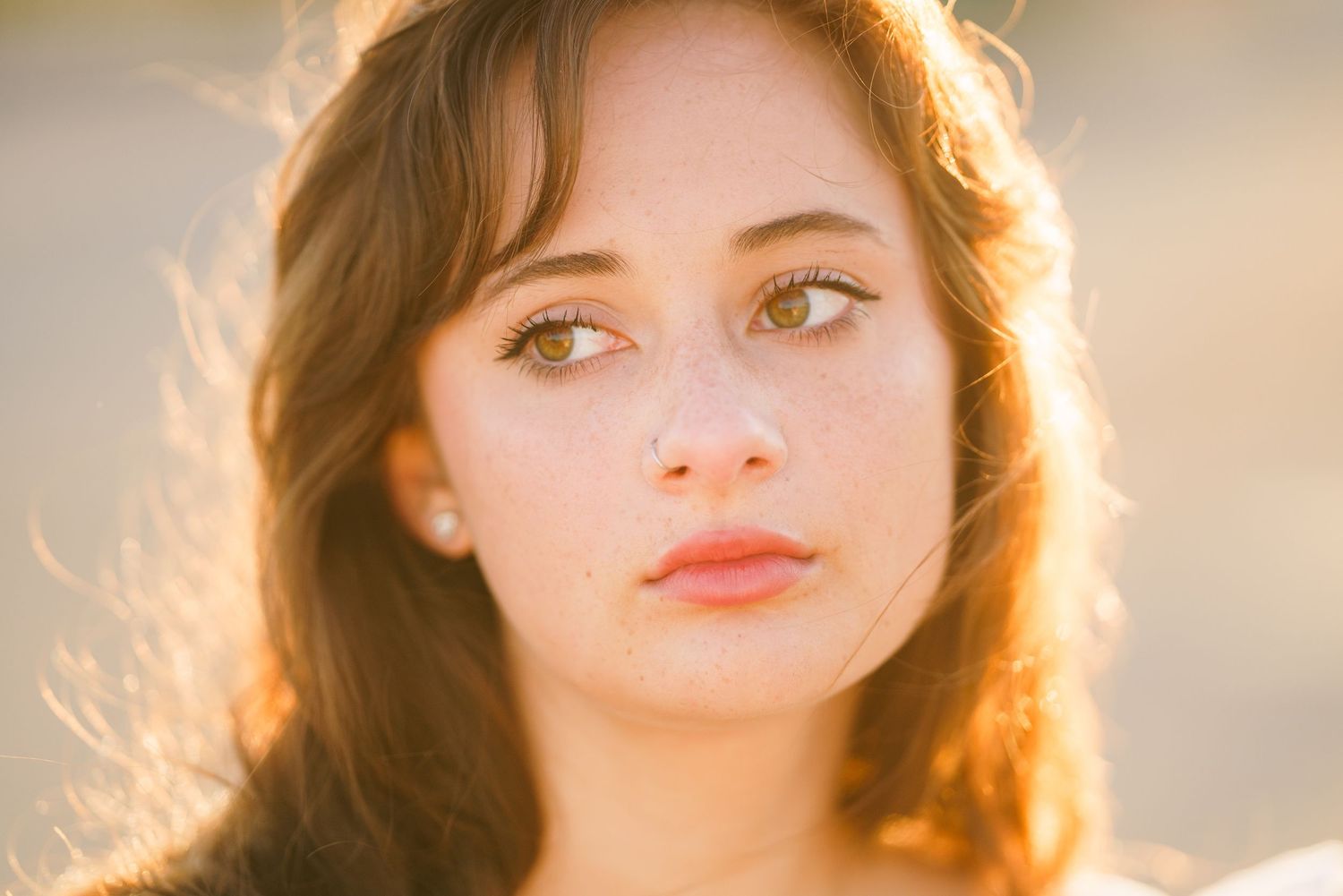 A backlit portrait shot against golden sunlight creates a dreamy atmospheric effect with soft rim lighting.